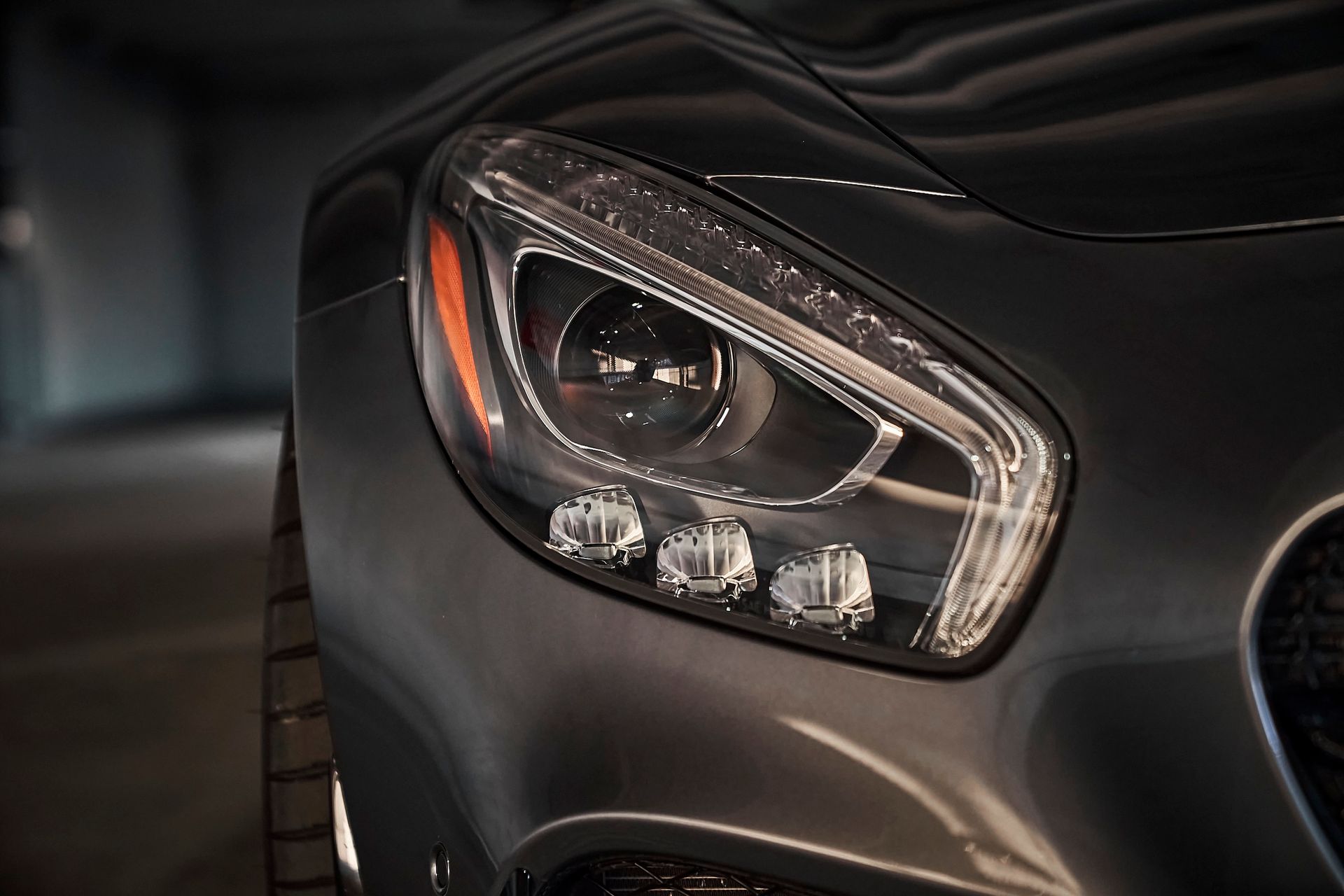 A close up of a car 's headlight in a parking lot.