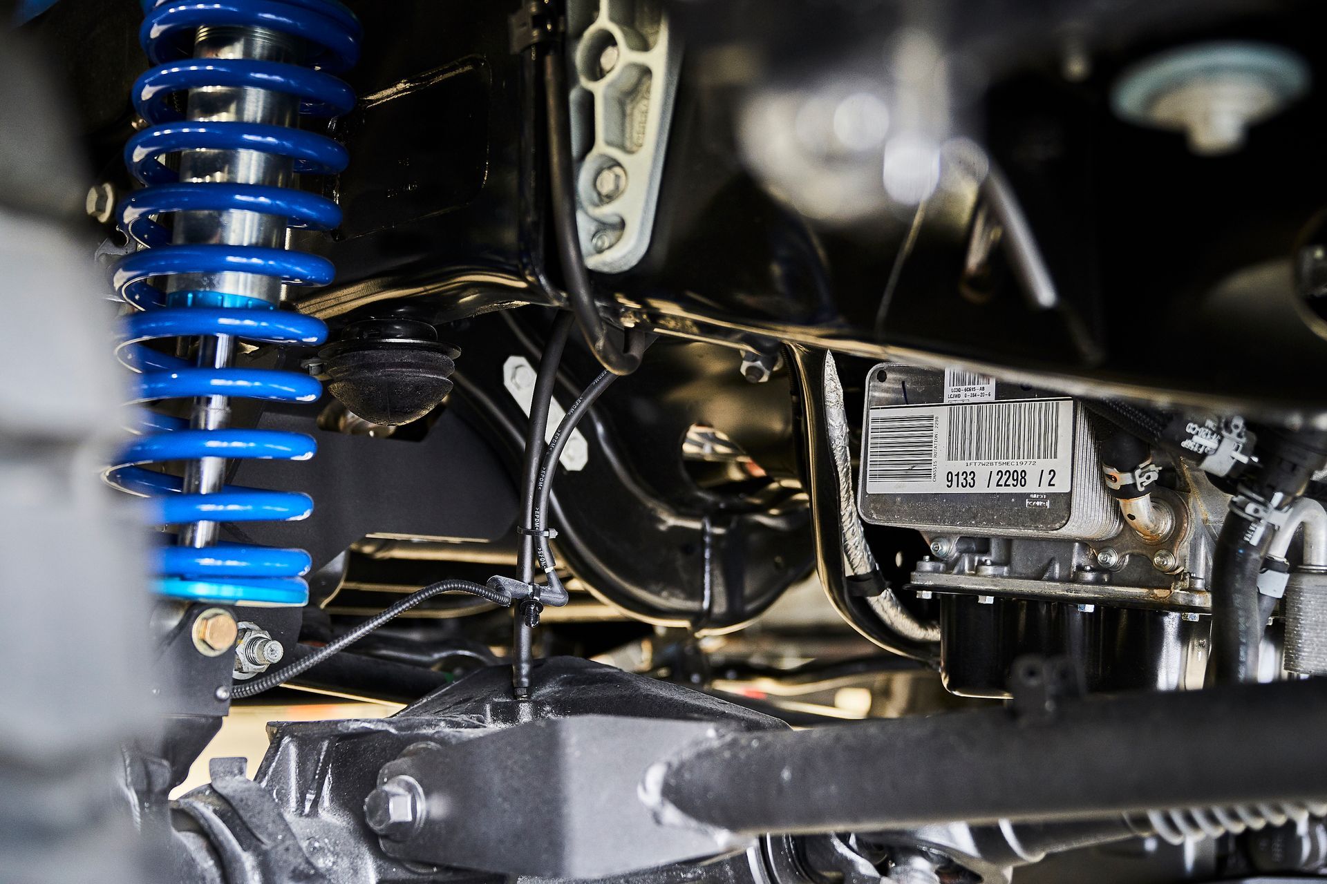 A close up of the underside of a car with a blue shock absorber.