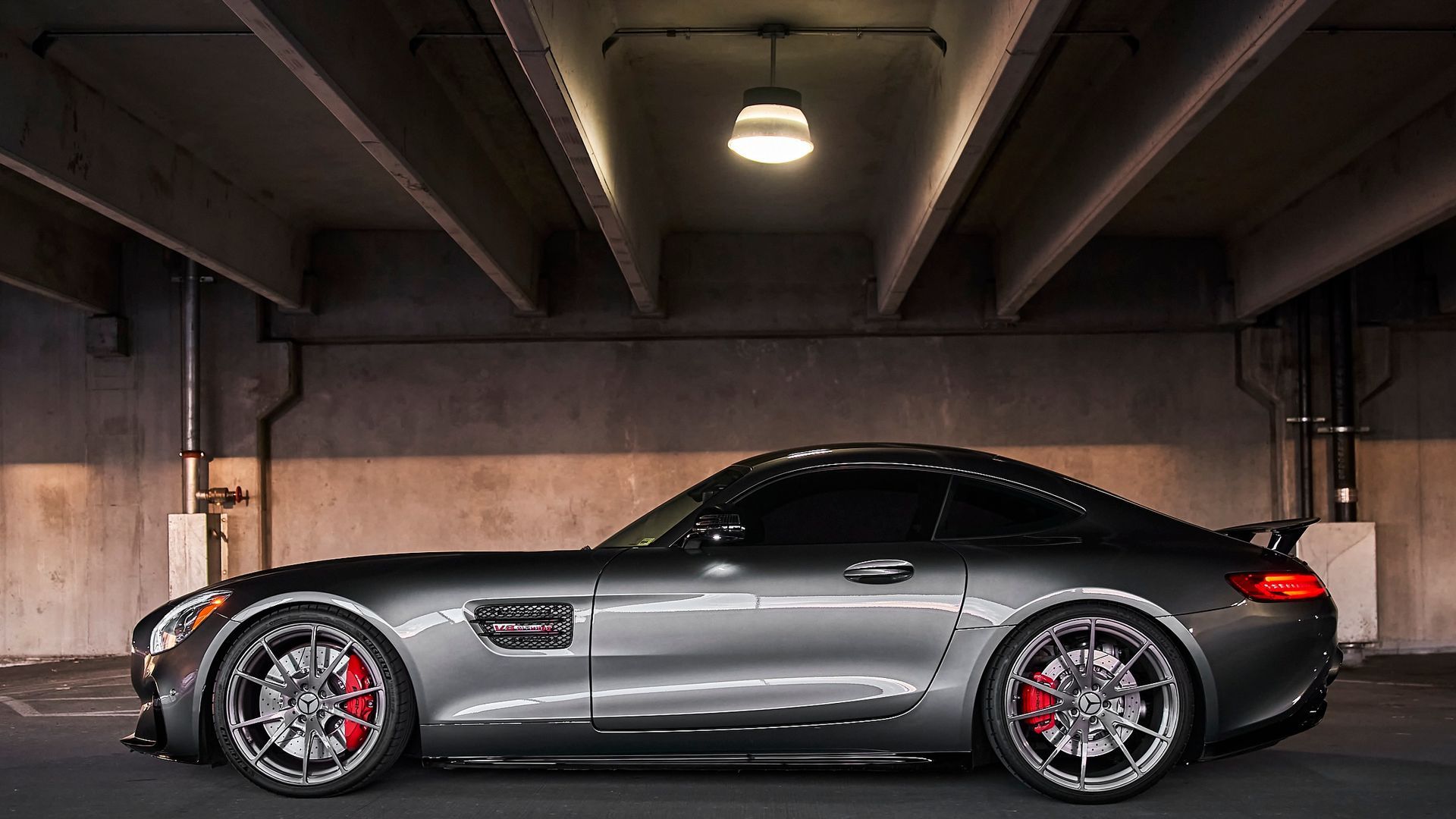 A mercedes amg gt is parked in a garage under a bridge.