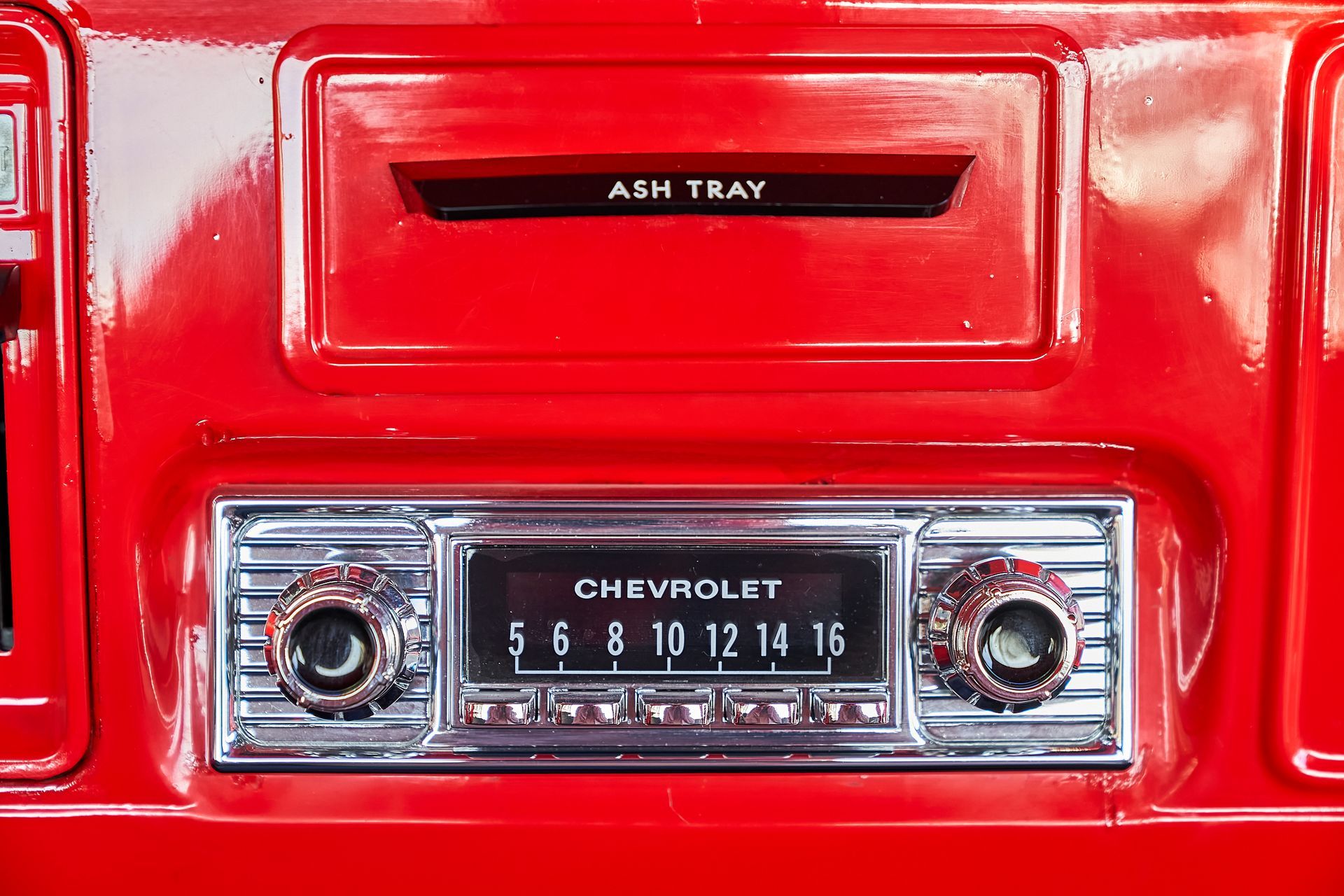 A close up of a chevrolet radio in a red car.