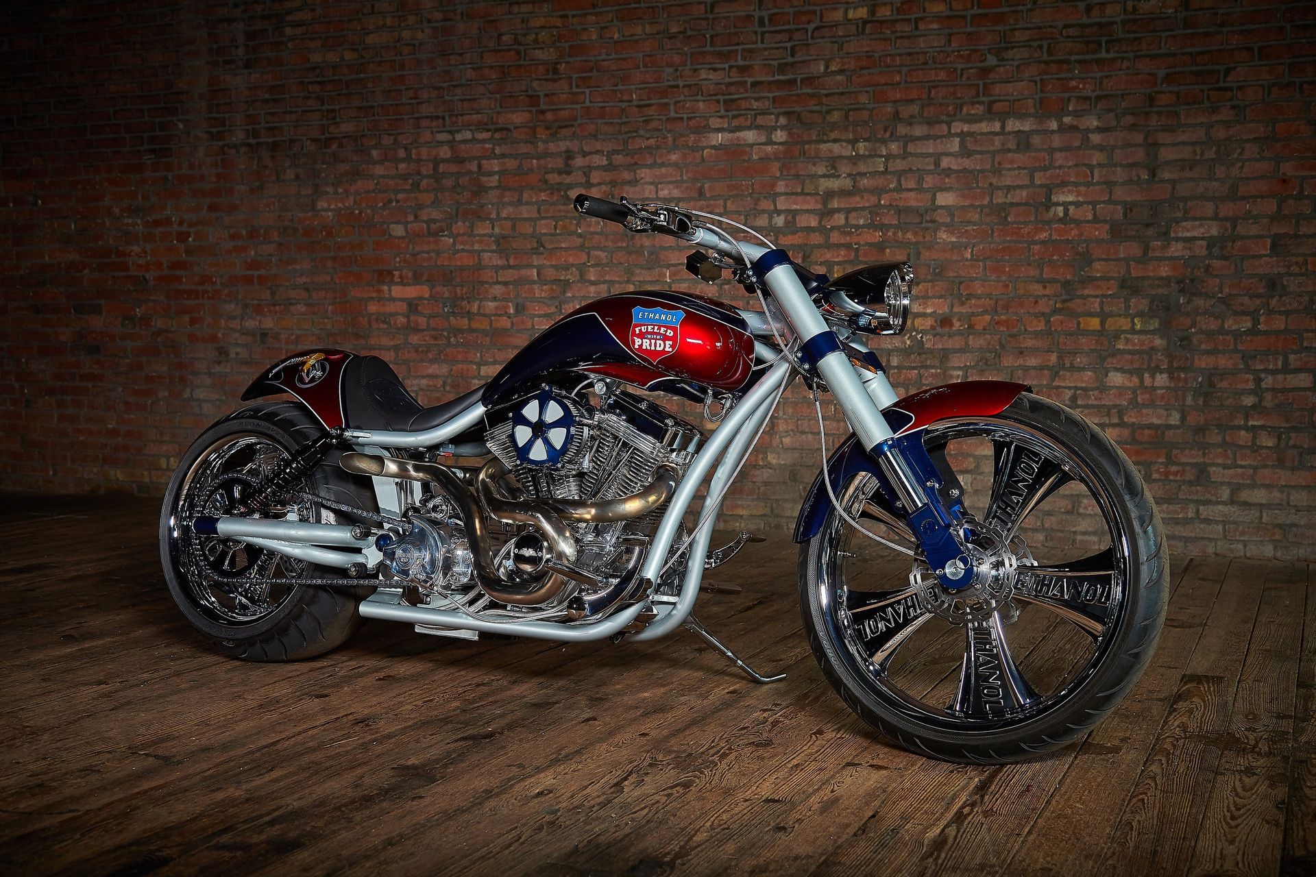 A red , white and blue motorcycle is parked in front of a brick wall.