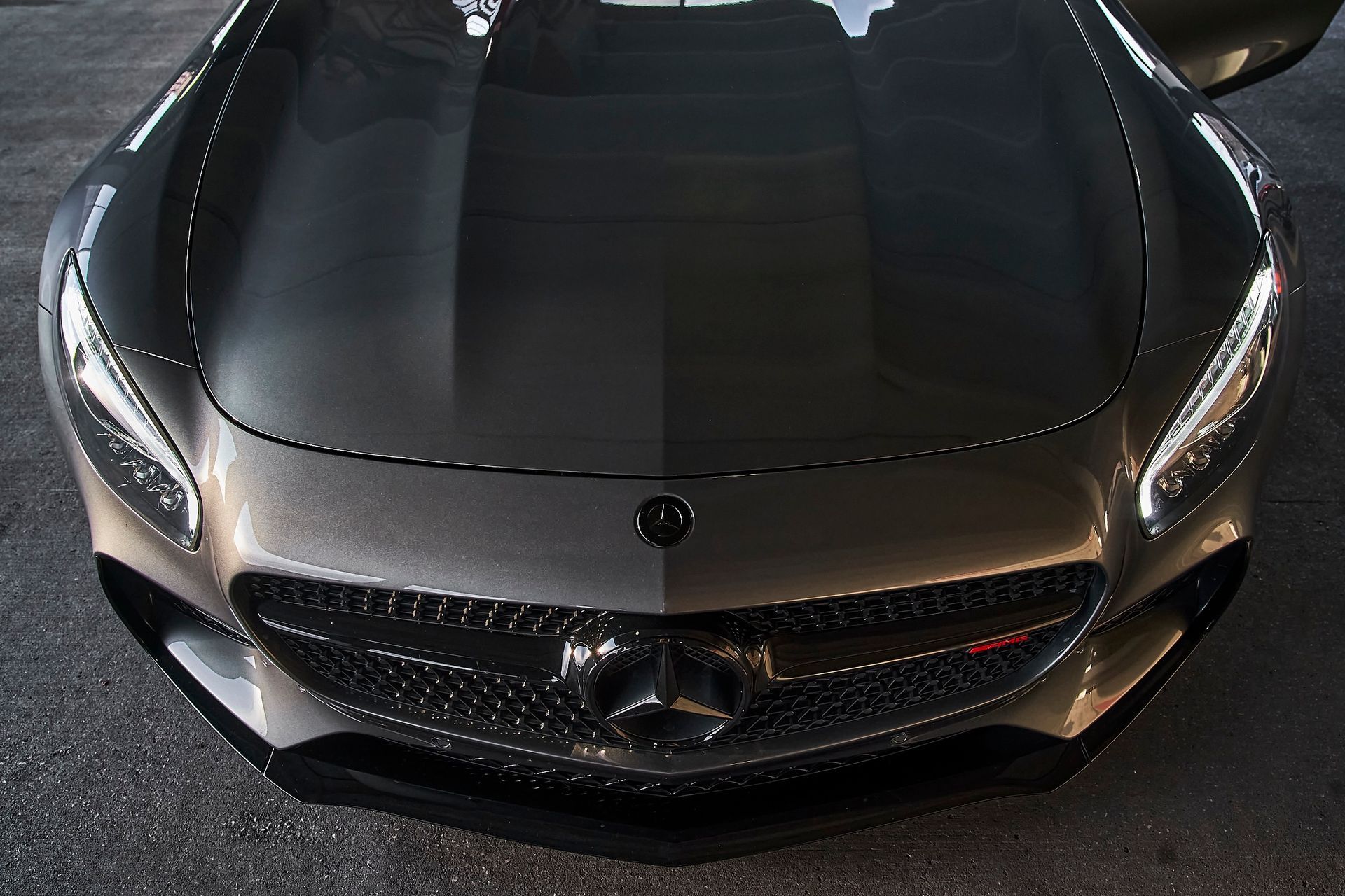 A close up of a black mercedes with the hood open
