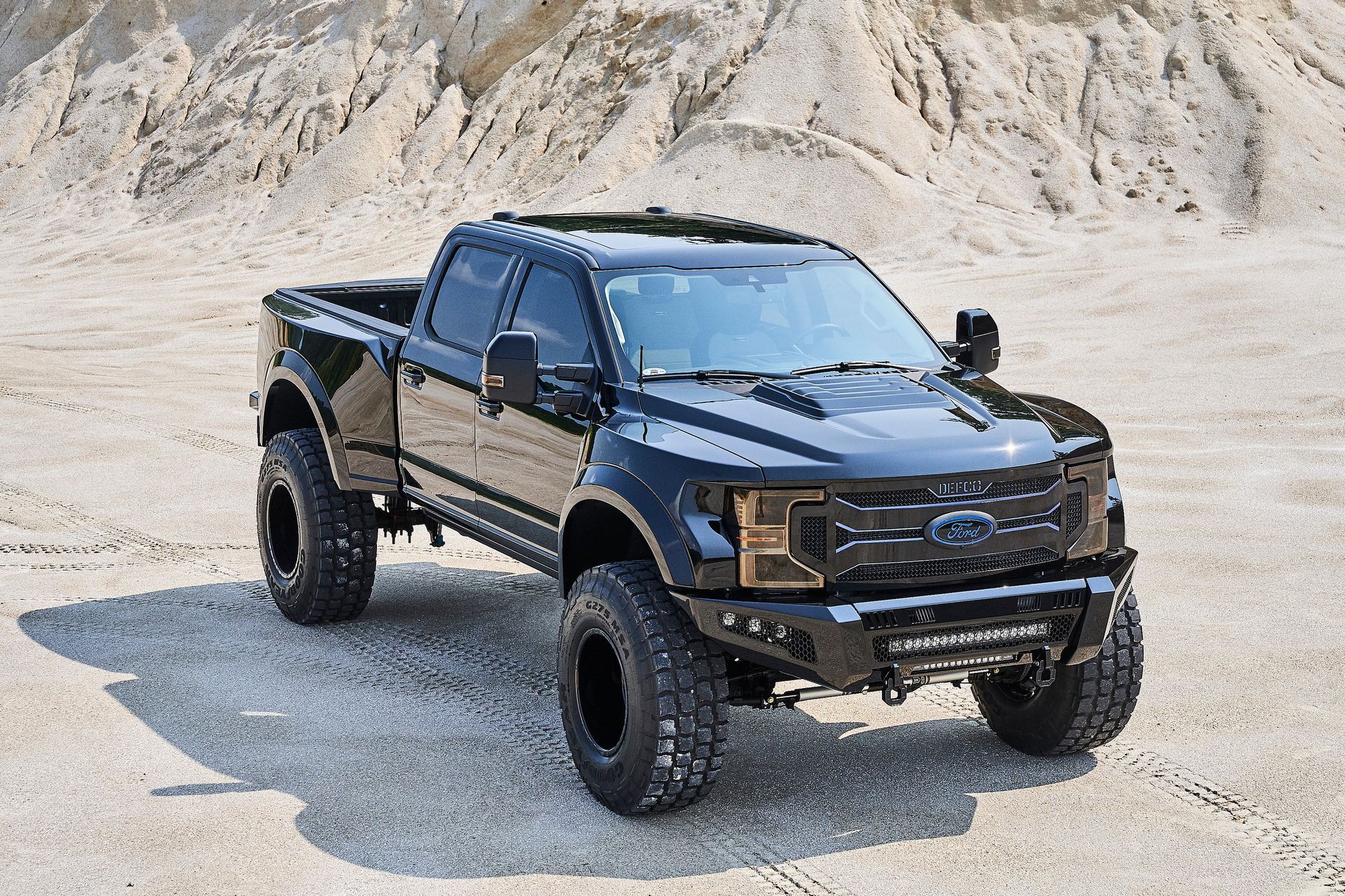 A black pickup truck is parked in a dirt field.