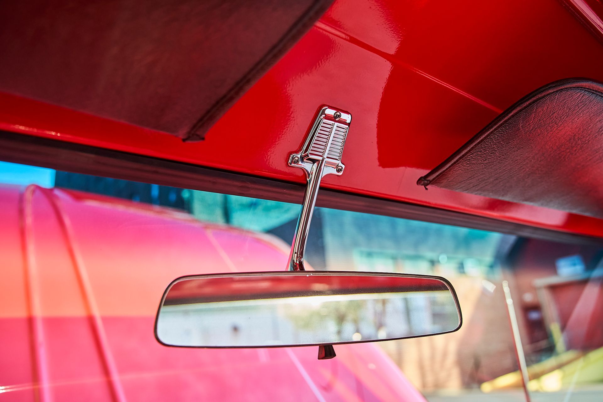 A red car with a rear view mirror hanging from the ceiling.