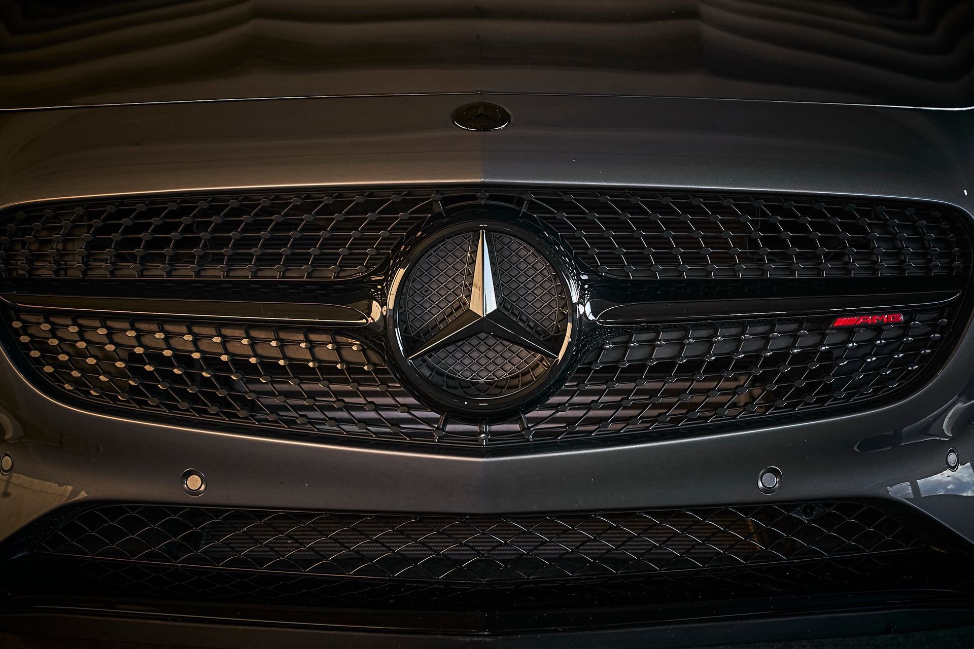 A close up of a mercedes benz logo on the front of a car.