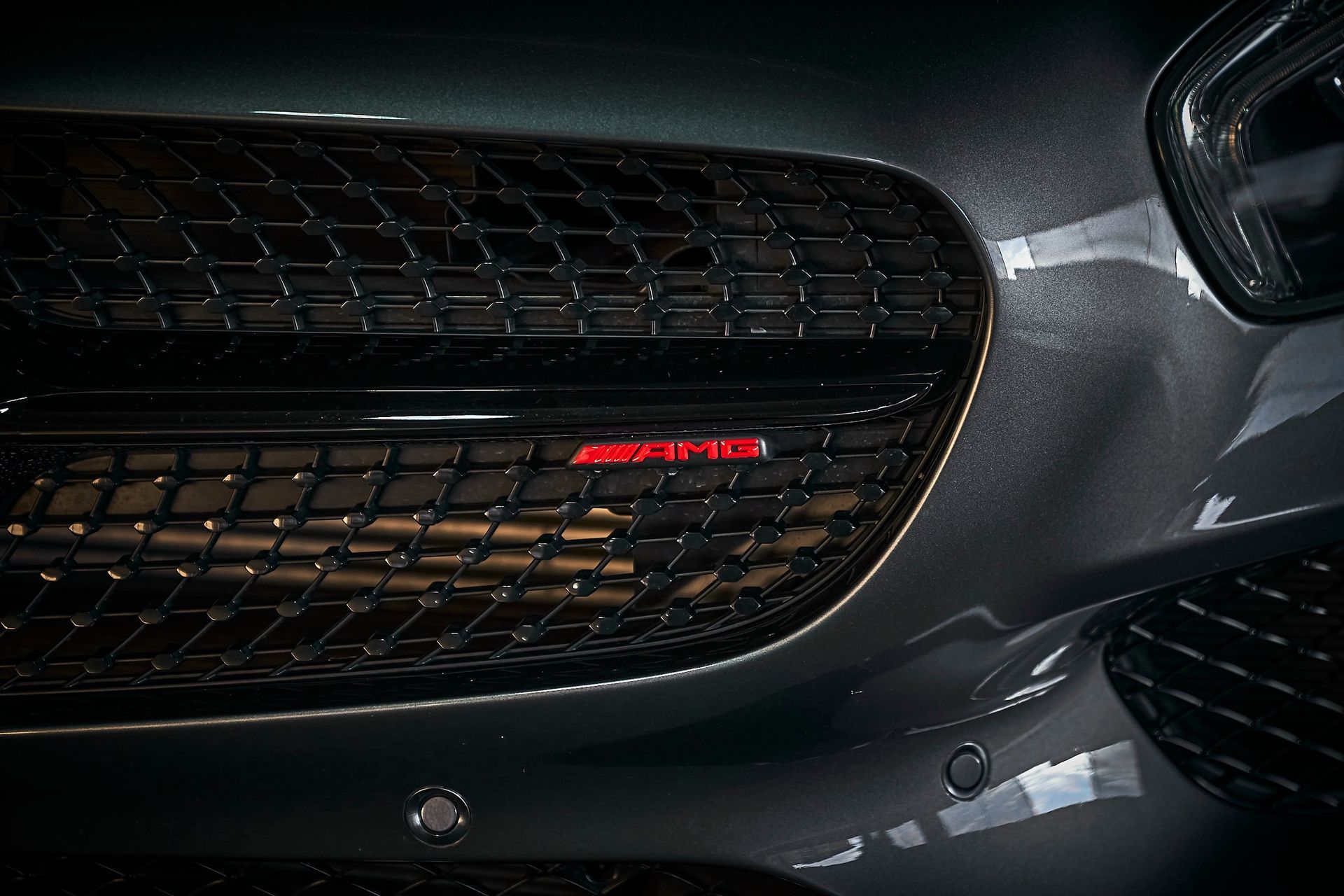 A close up of a car 's front grille with a red logo on it.