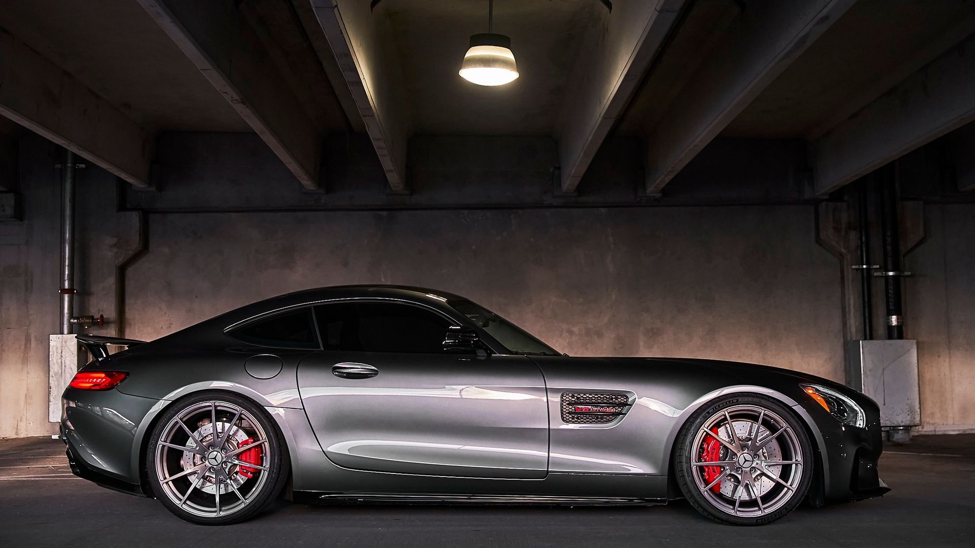 A mercedes amg gt is parked in a garage under a bridge.