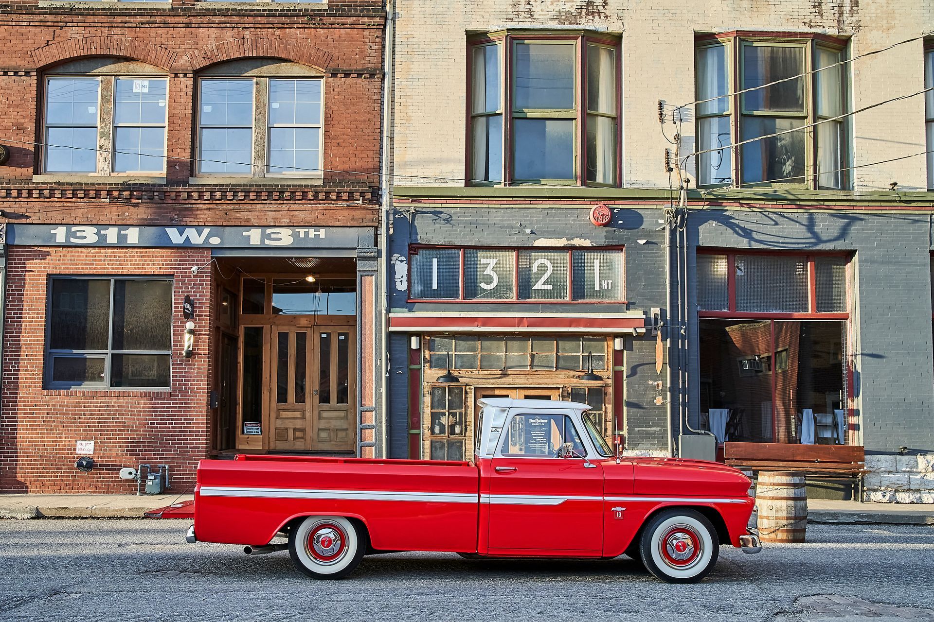 A red truck is parked in front of a building with the number 1311 on it