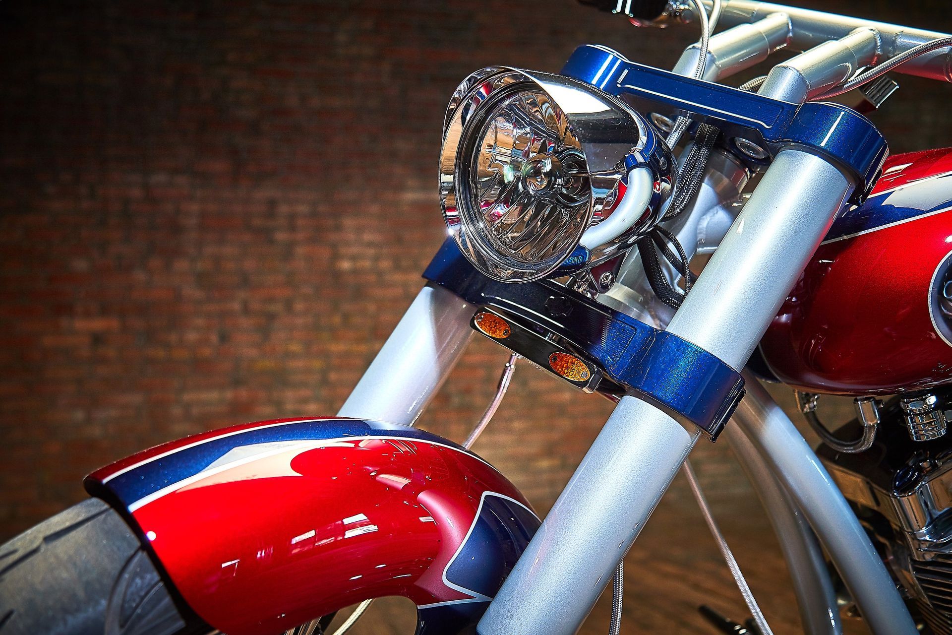A red white and blue motorcycle is parked in front of a brick wall