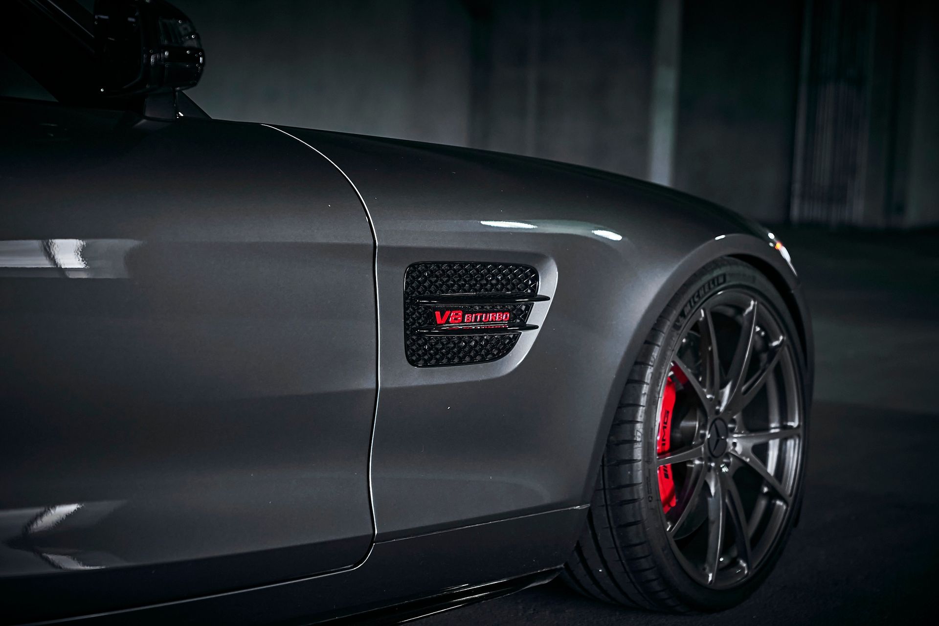 A close up of the side of a mercedes amg gt s with red brake calipers.