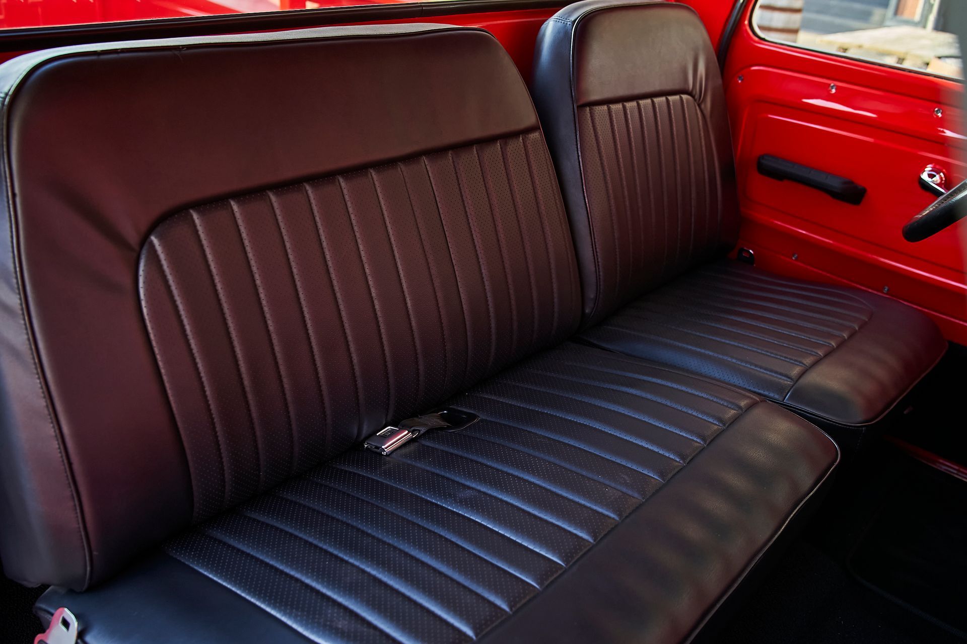 The back seat of a red truck with black leather seats