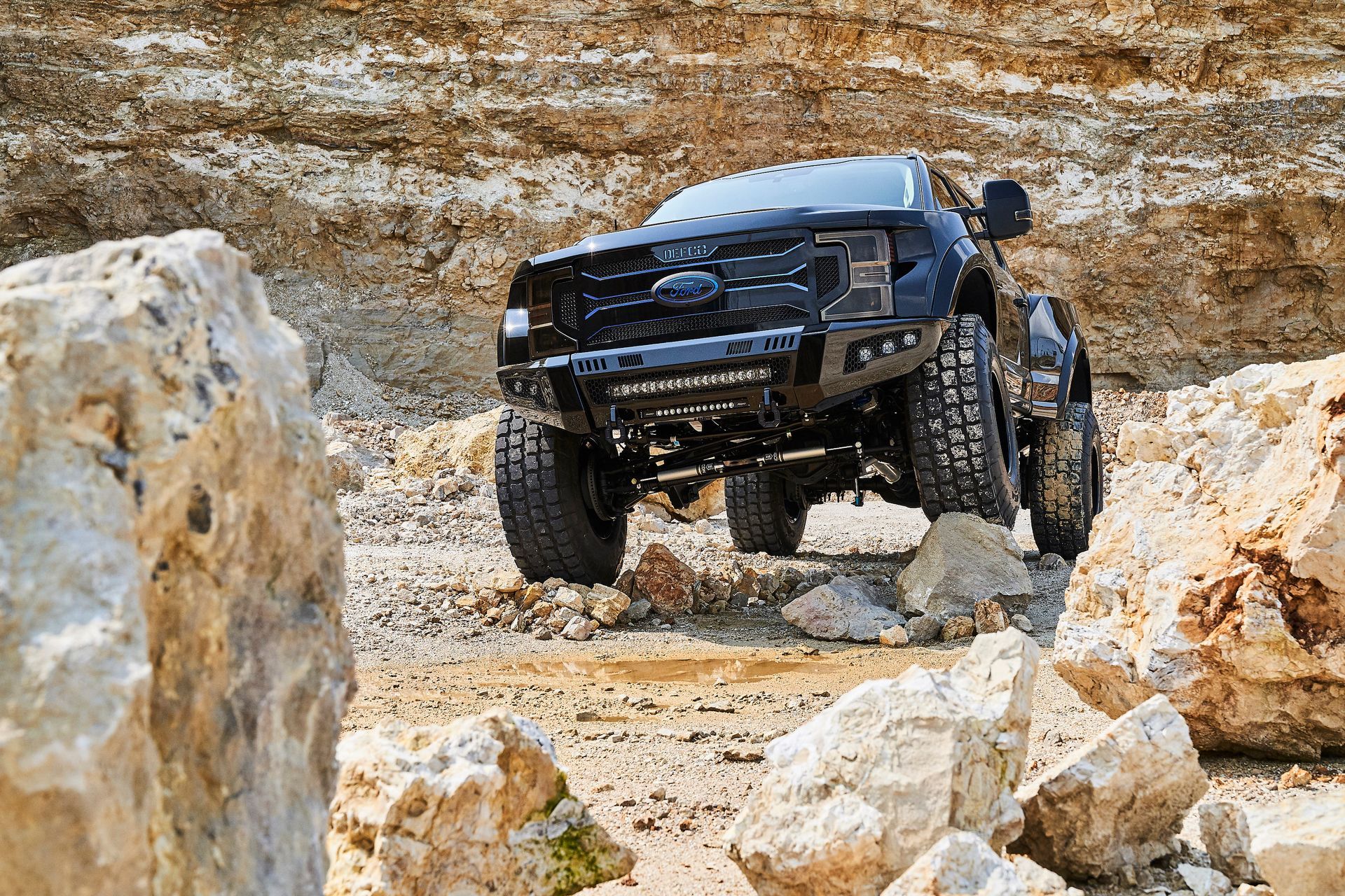A black truck is driving through a rocky area.