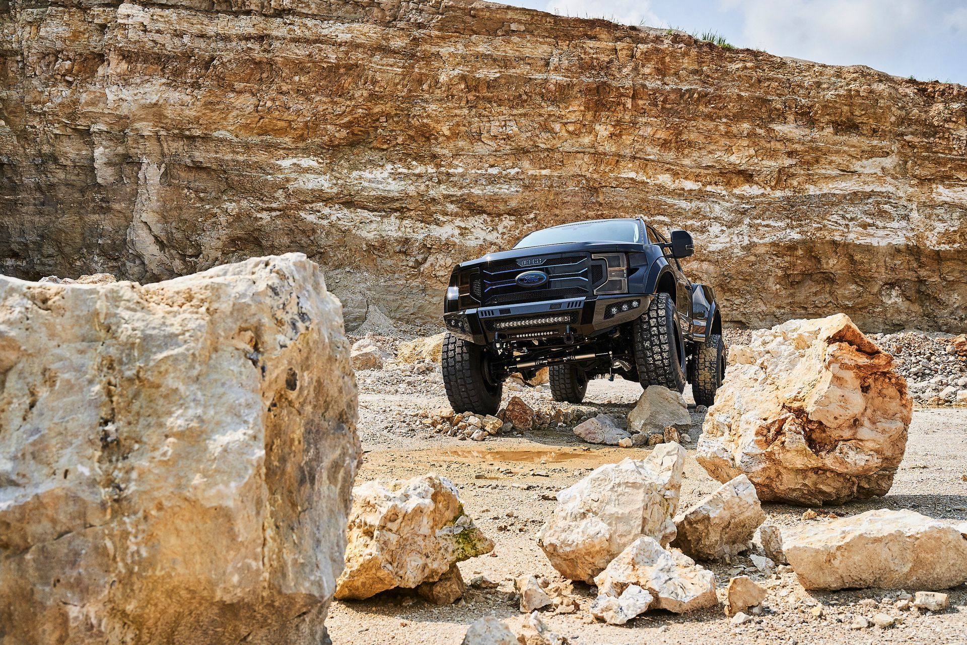 A black truck is driving through a rocky area.