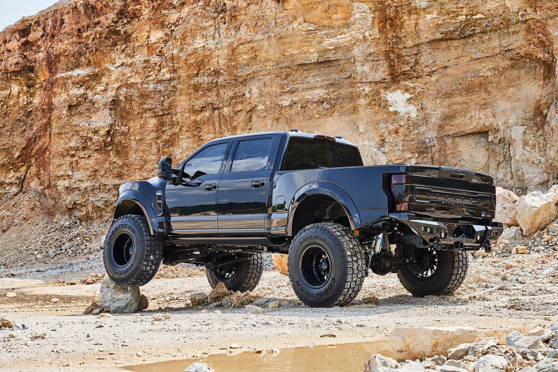 A black truck is parked on top of a rocky hillside.
