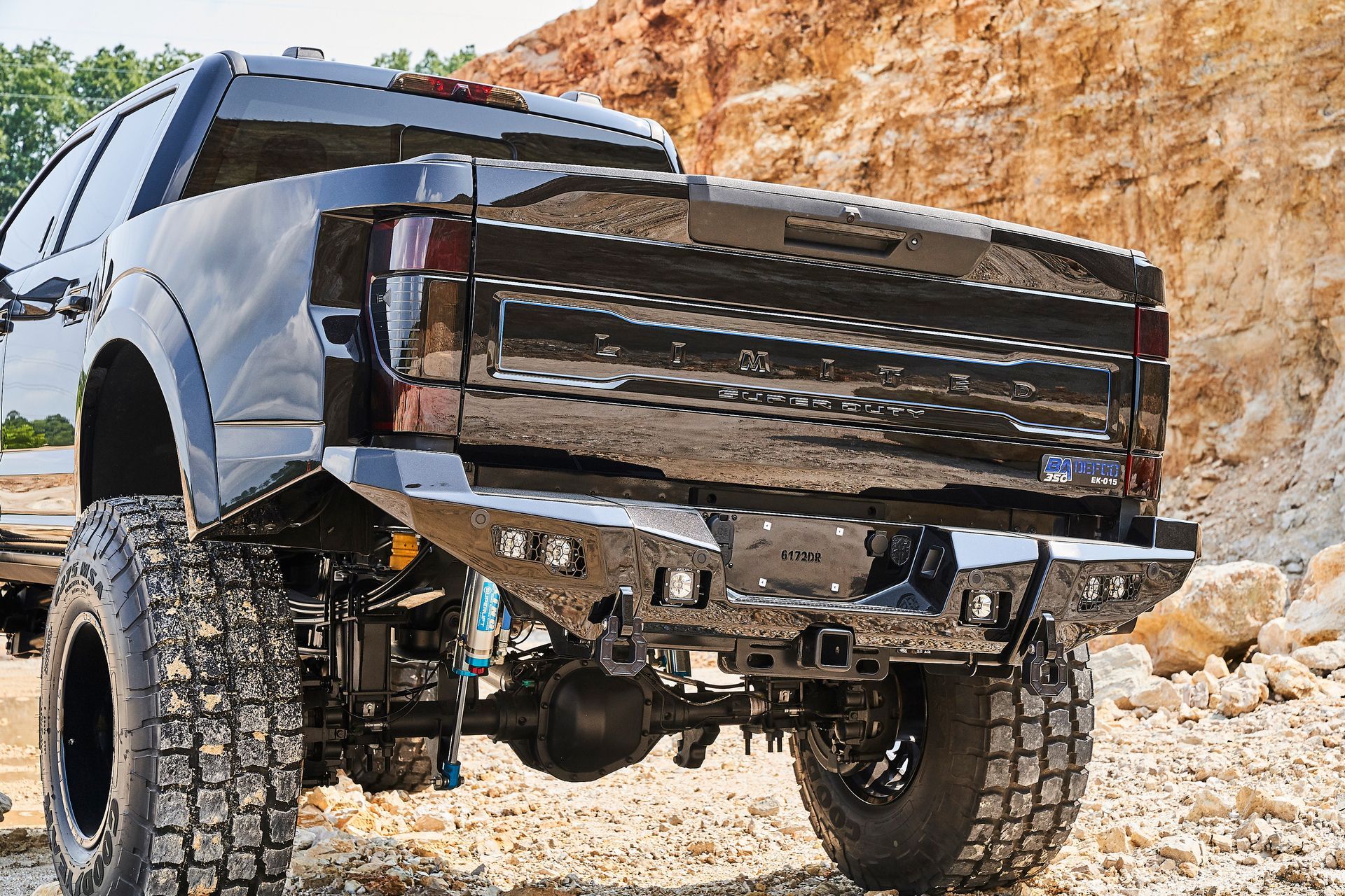 A black truck with a rear bumper is parked in the dirt.