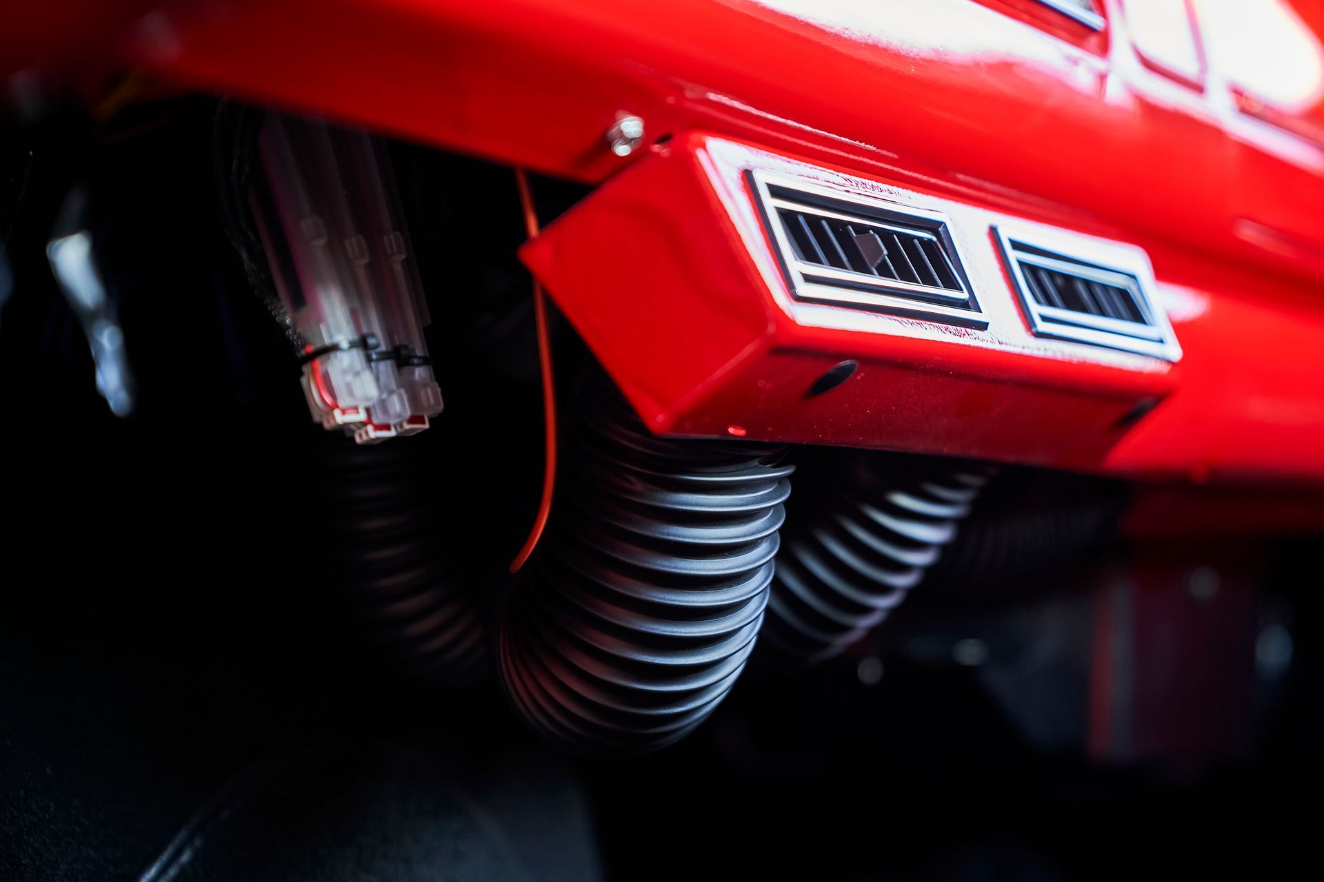 A close up of a red car with a hose attached to it.