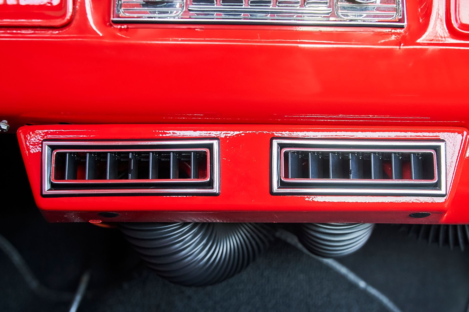 A red car has two air vents on the dashboard