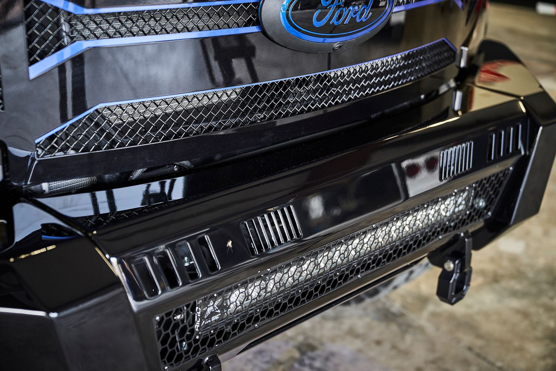 A close up of a ford truck 's front bumper with a light on it.