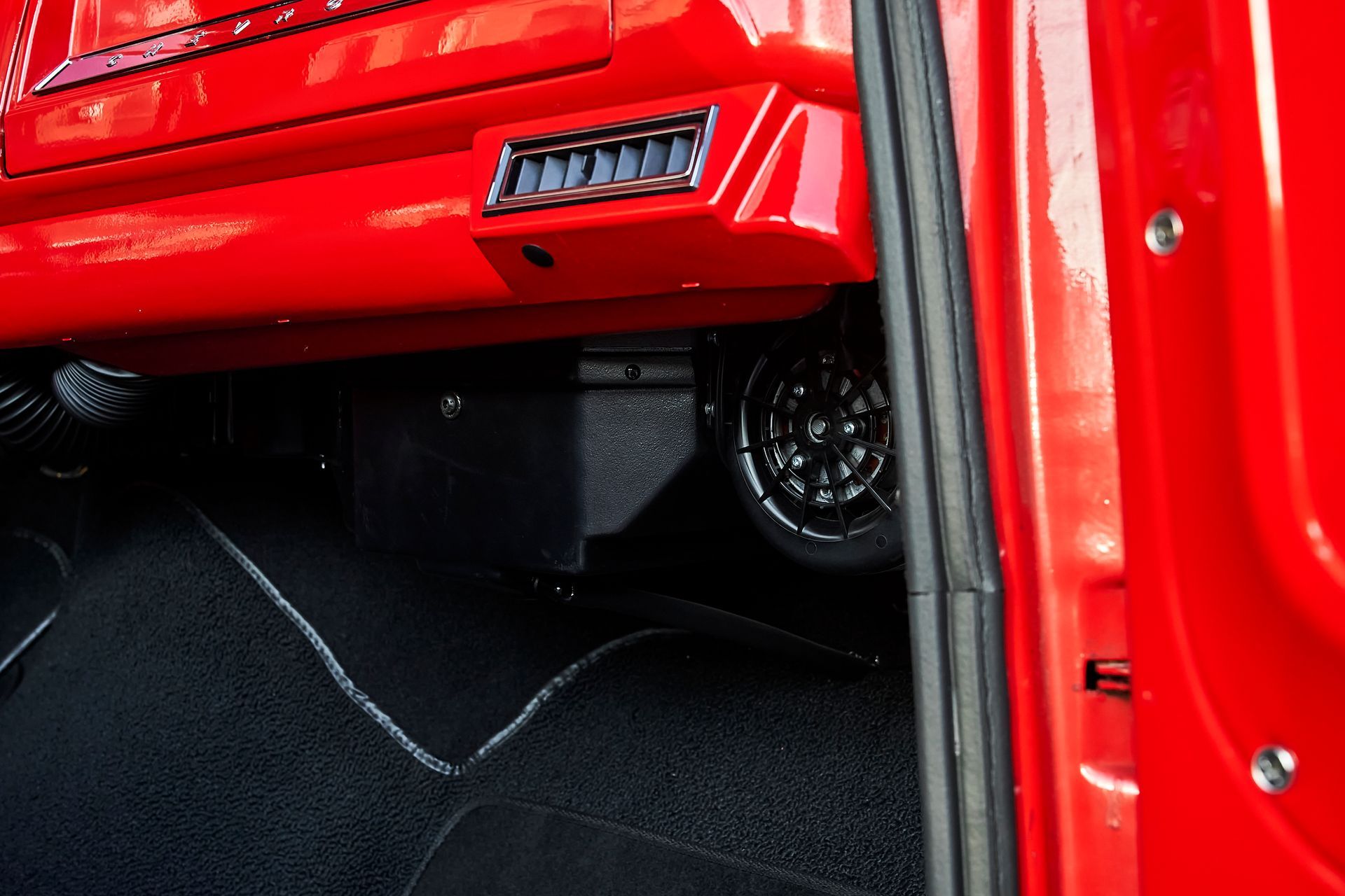 A red car with a black mat underneath it