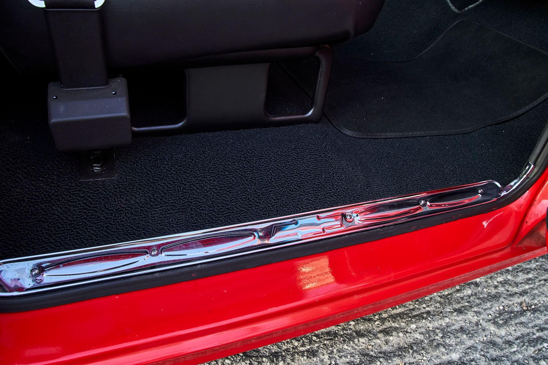 A red car with a black mat on the floor