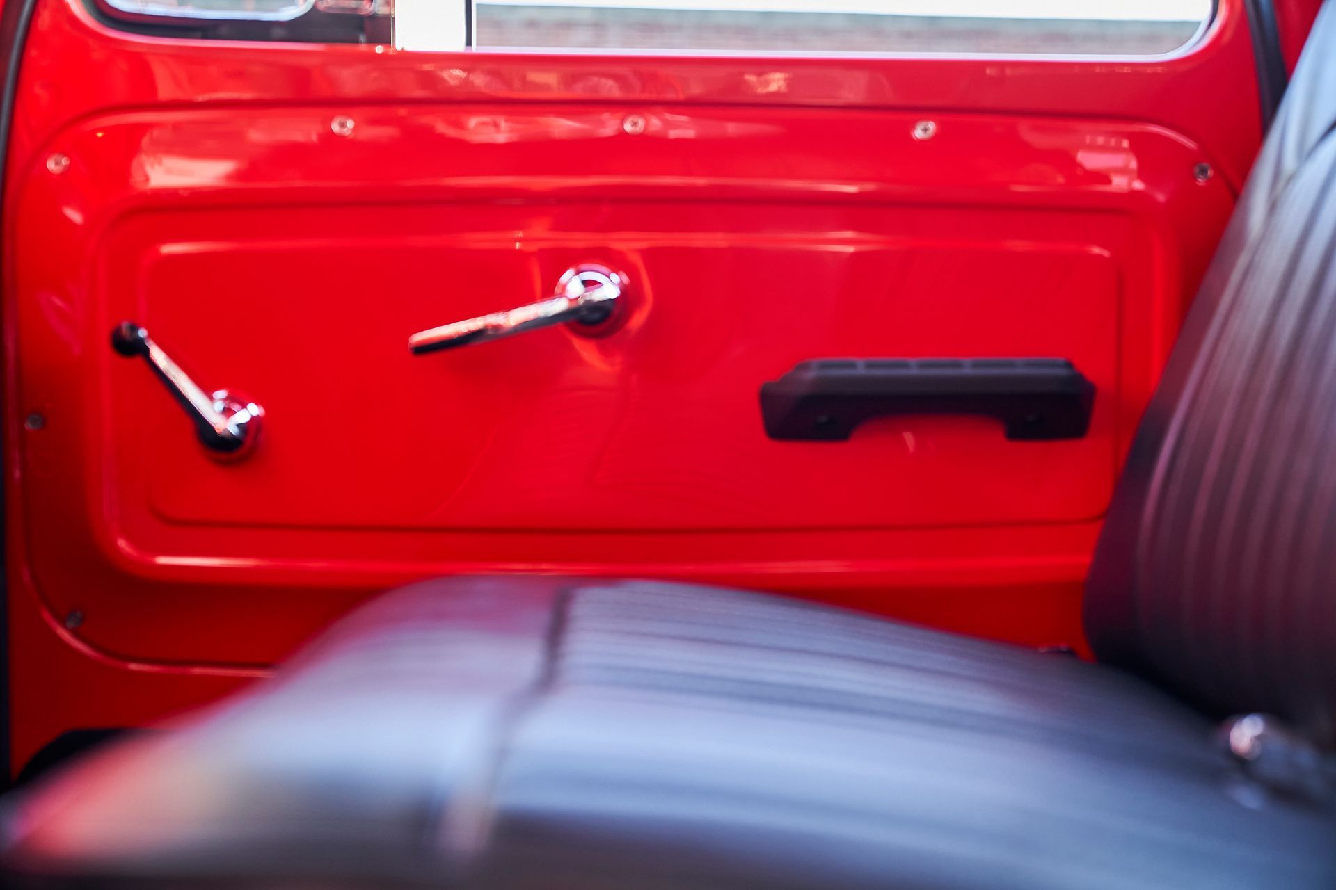 The inside of a red car with black seats and door handles.