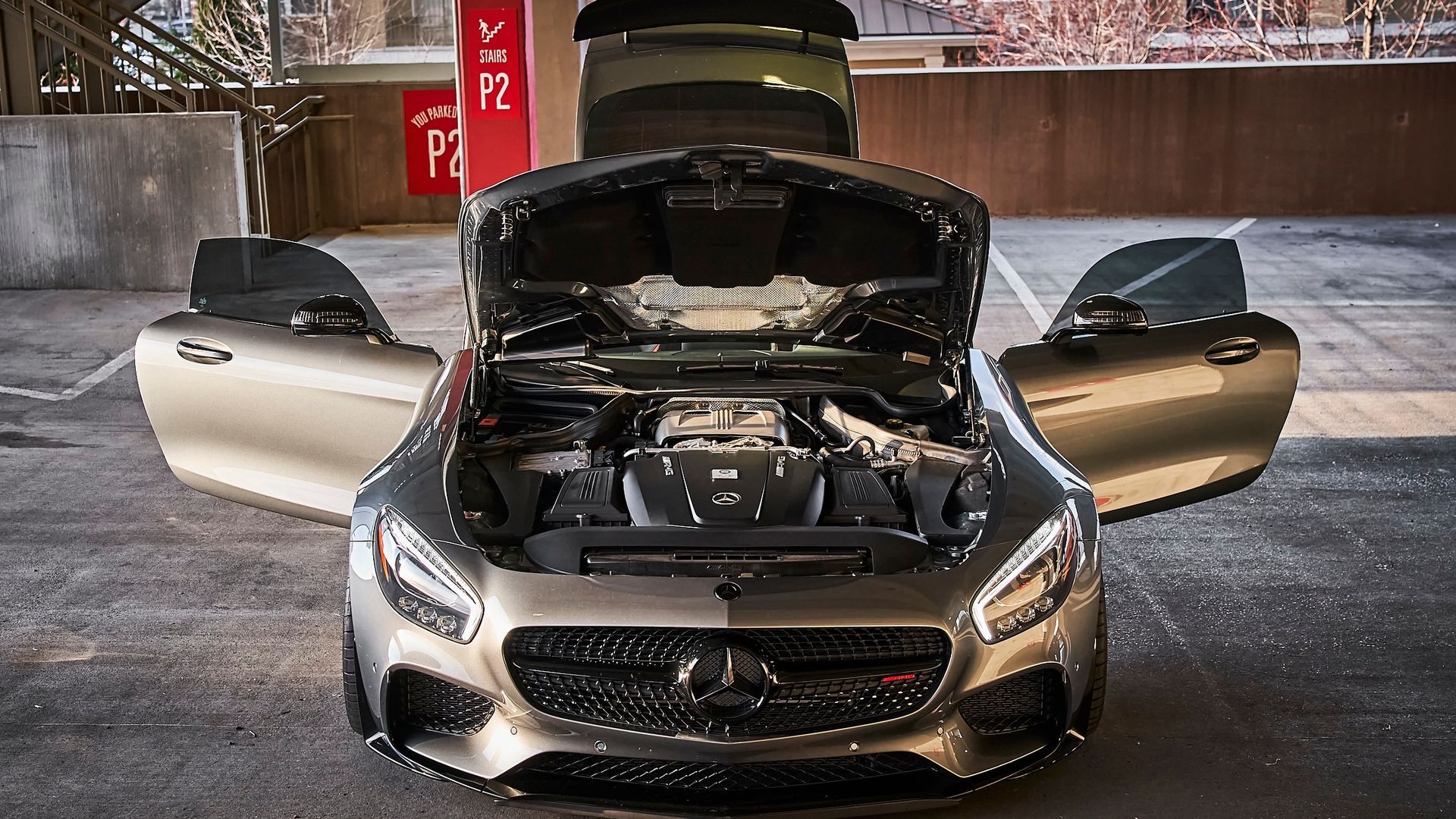 A mercedes with its hood open is parked in a parking lot