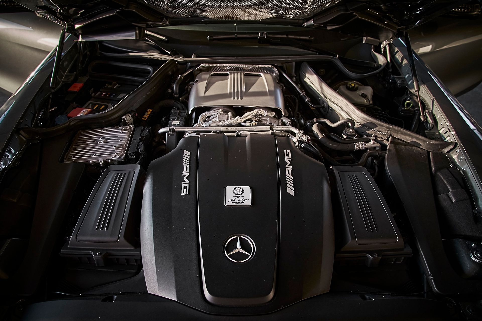 A close up of a mercedes engine with the hood open