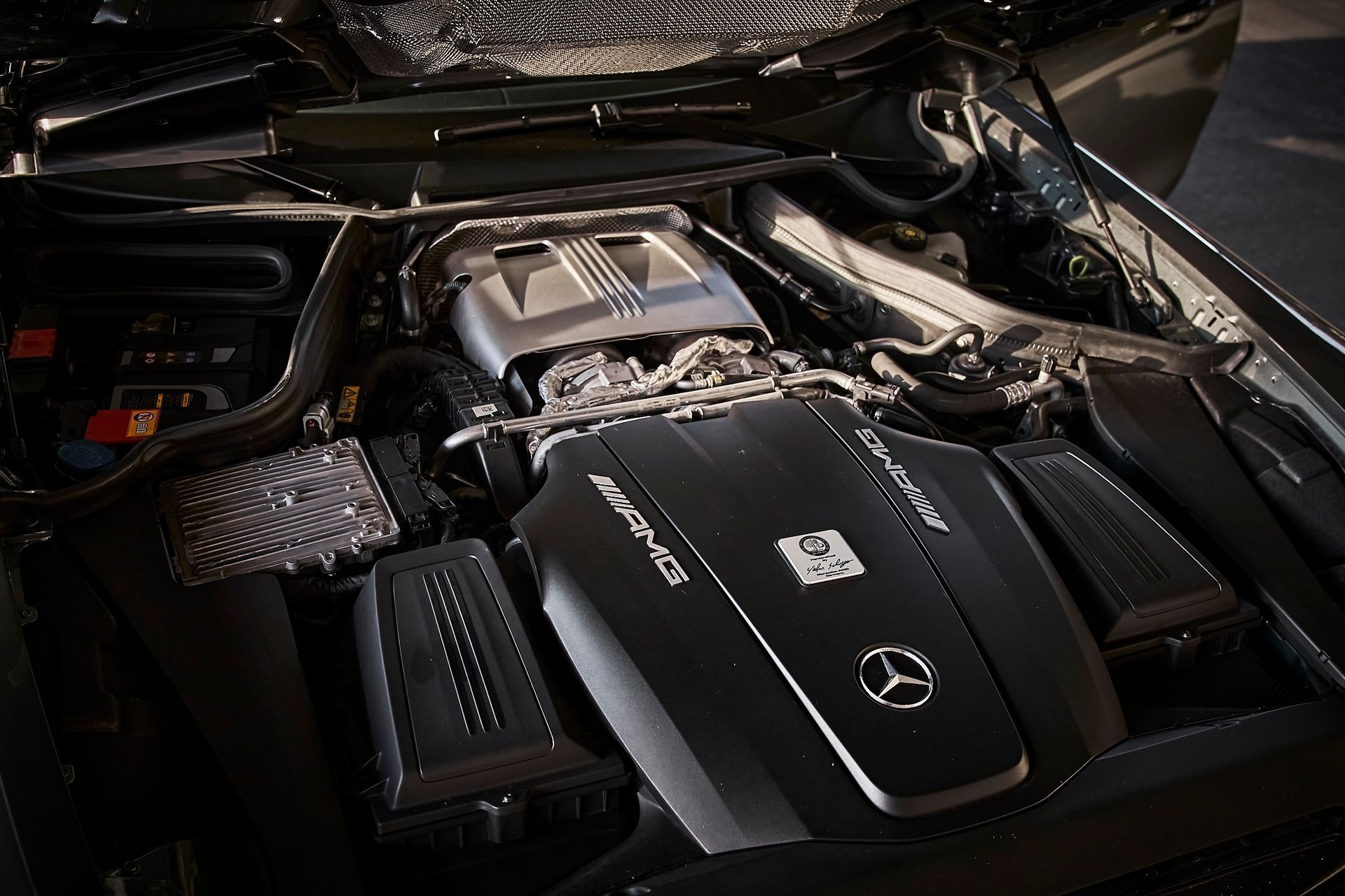 The engine of a mercedes benz is shown with the hood open.