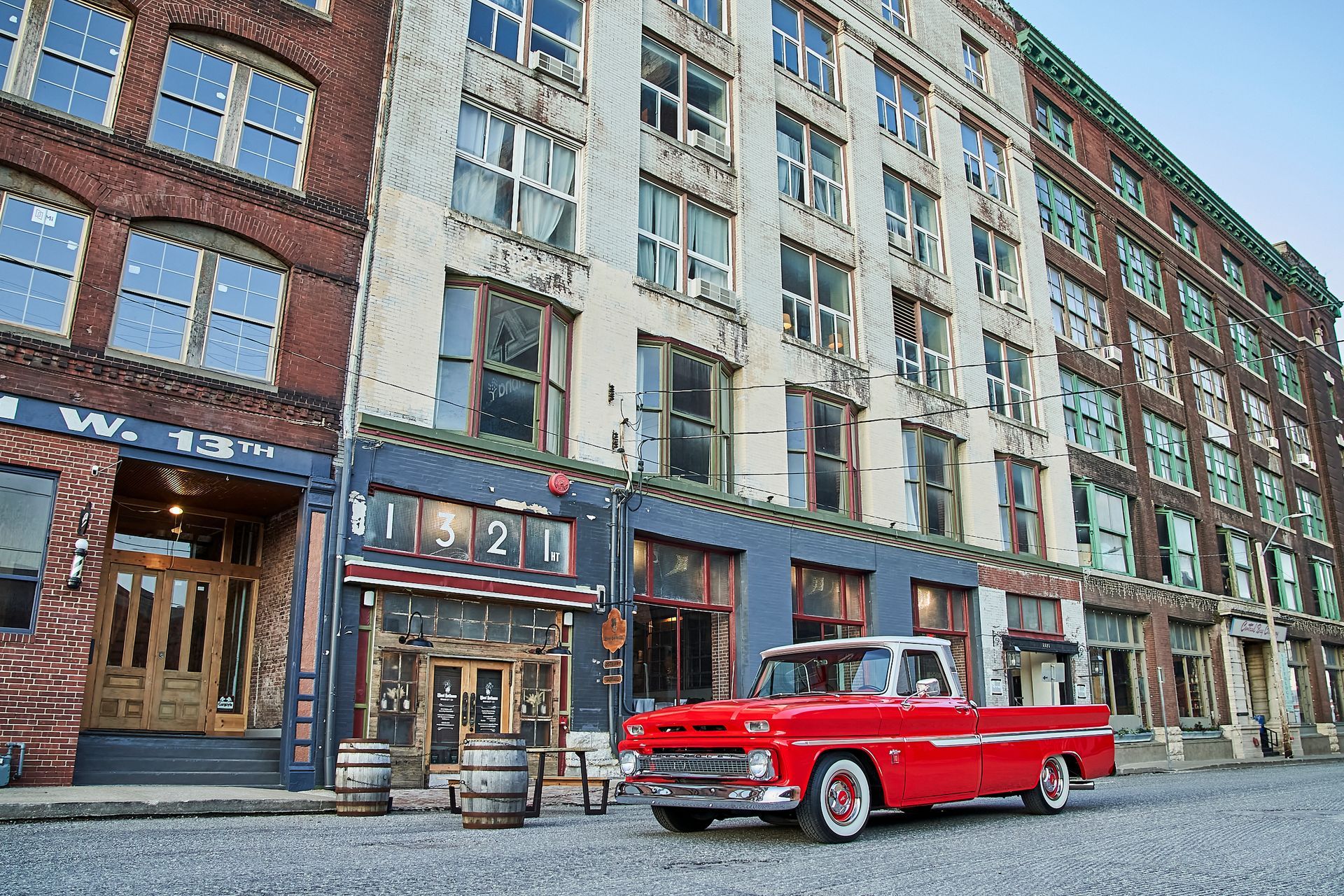 A red truck is parked in front of a large building.