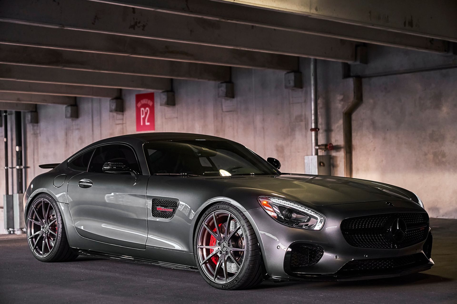 A mercedes amg gt is parked in a parking garage under a bridge.