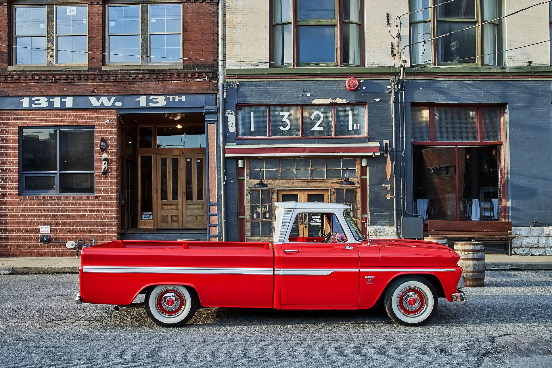 A red truck is parked in front of a building that says 1311 w. 13th