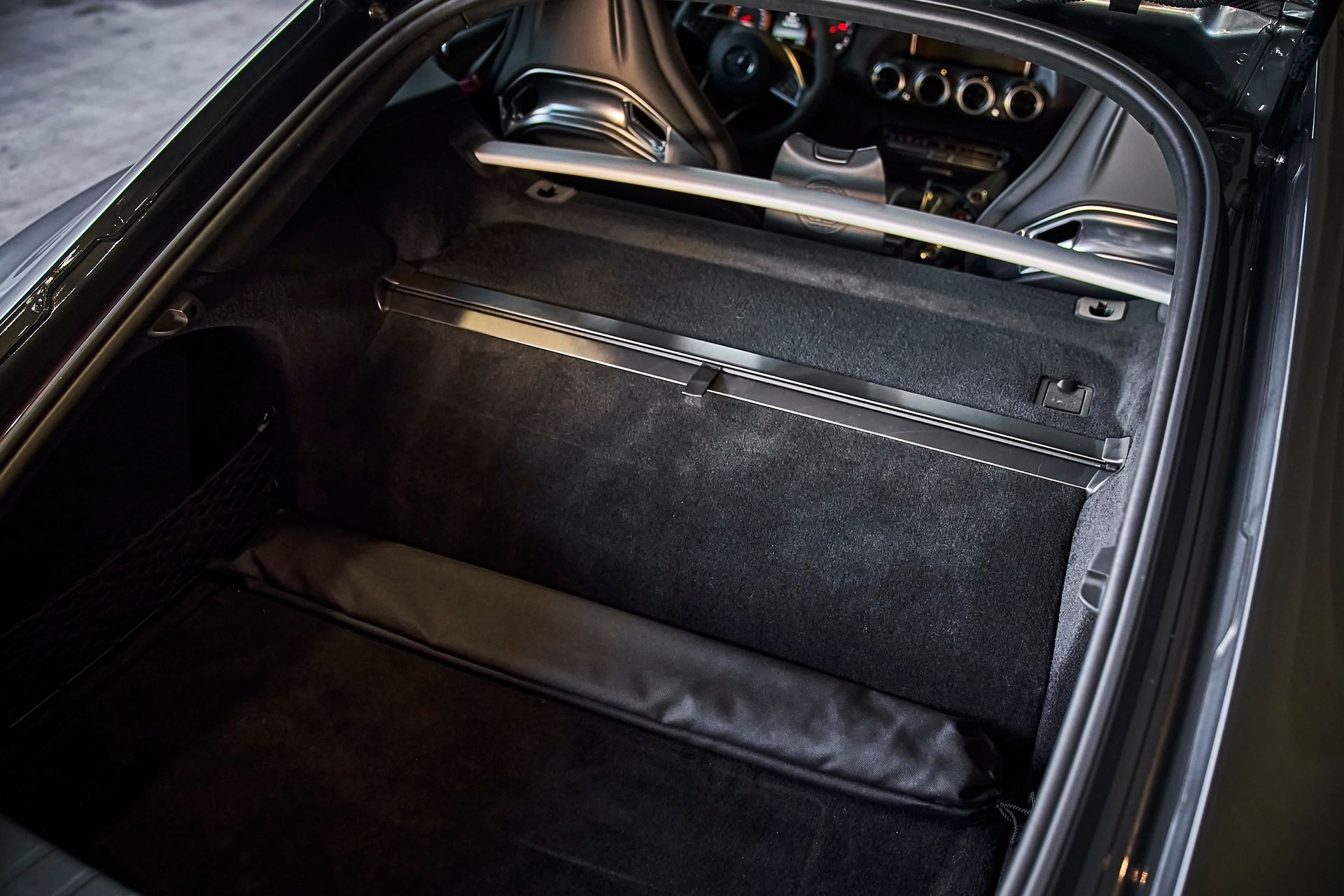 The trunk of a black sports car with a bag in it
