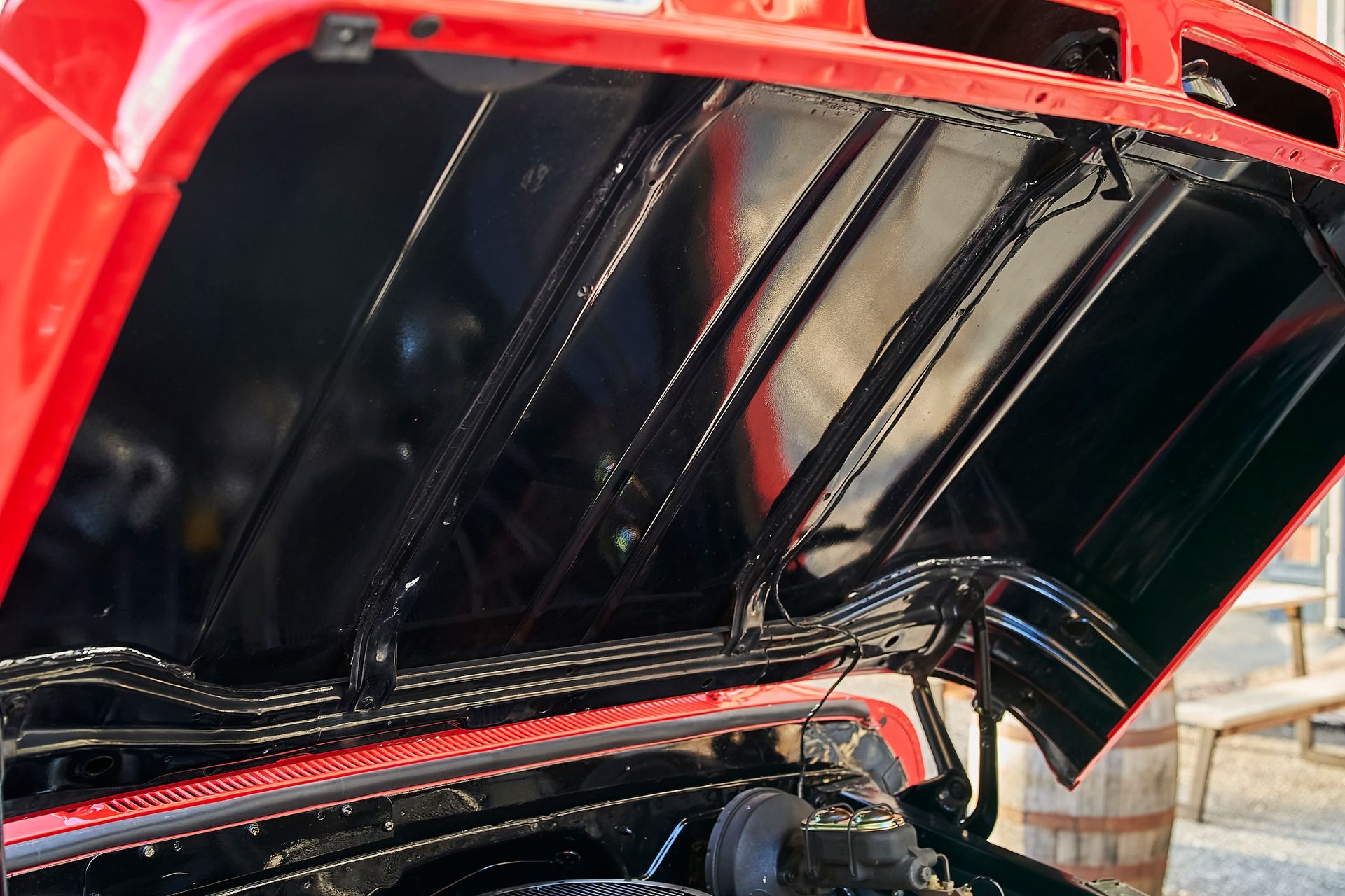 The hood of a red car is open and the engine is visible