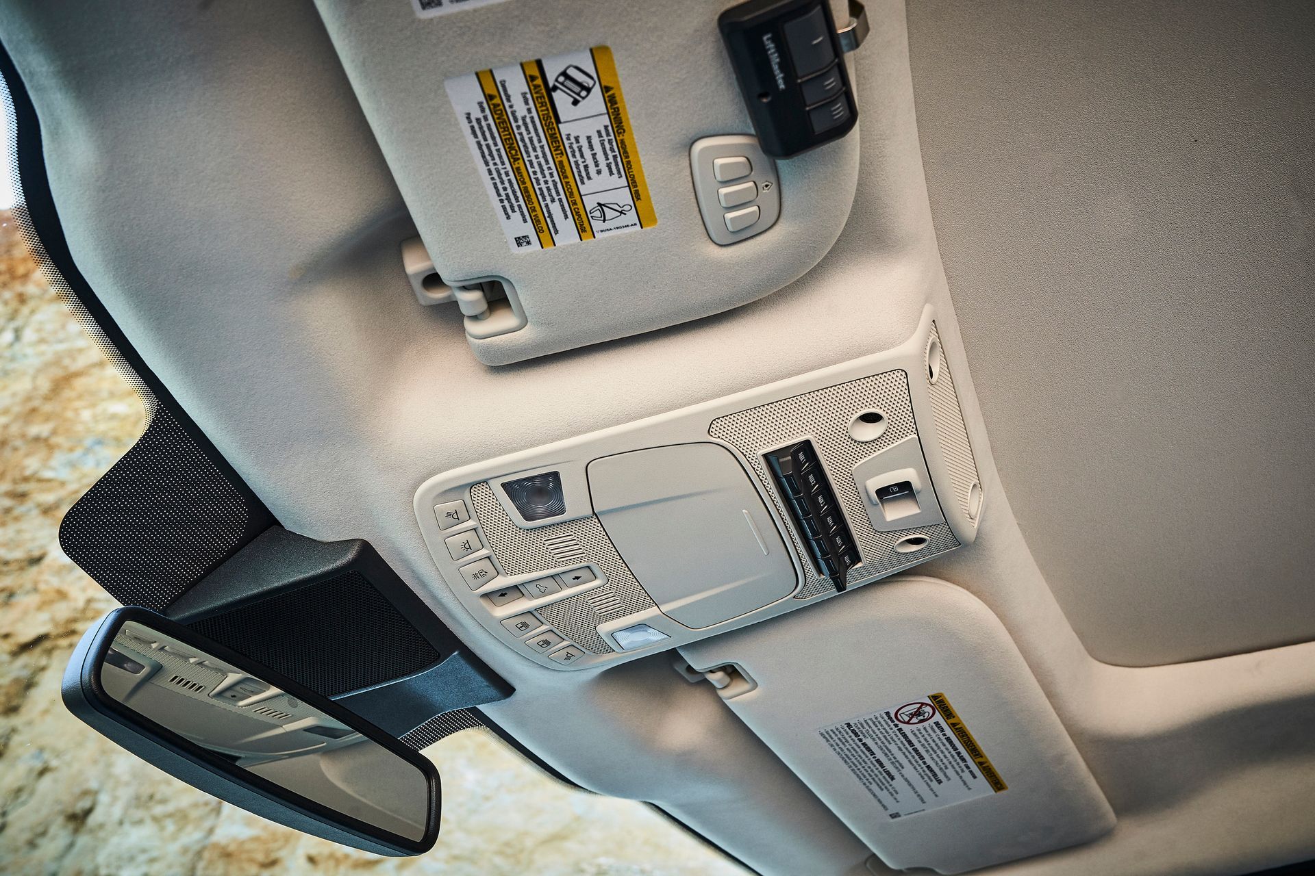 The ceiling of a car with sun visors and a rear view mirror.