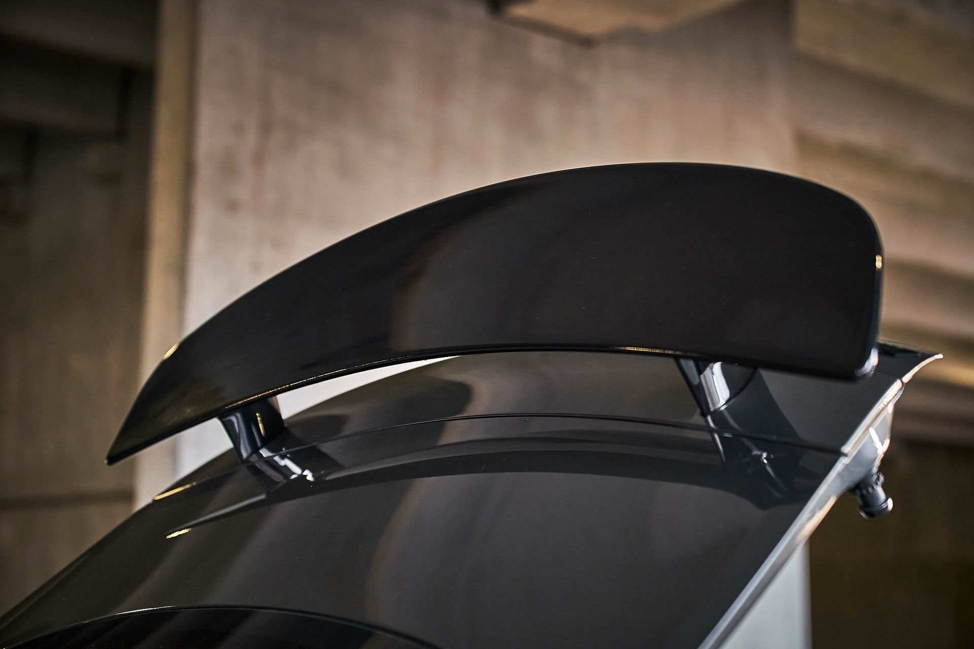 A close up of a car 's rear wing in a garage.