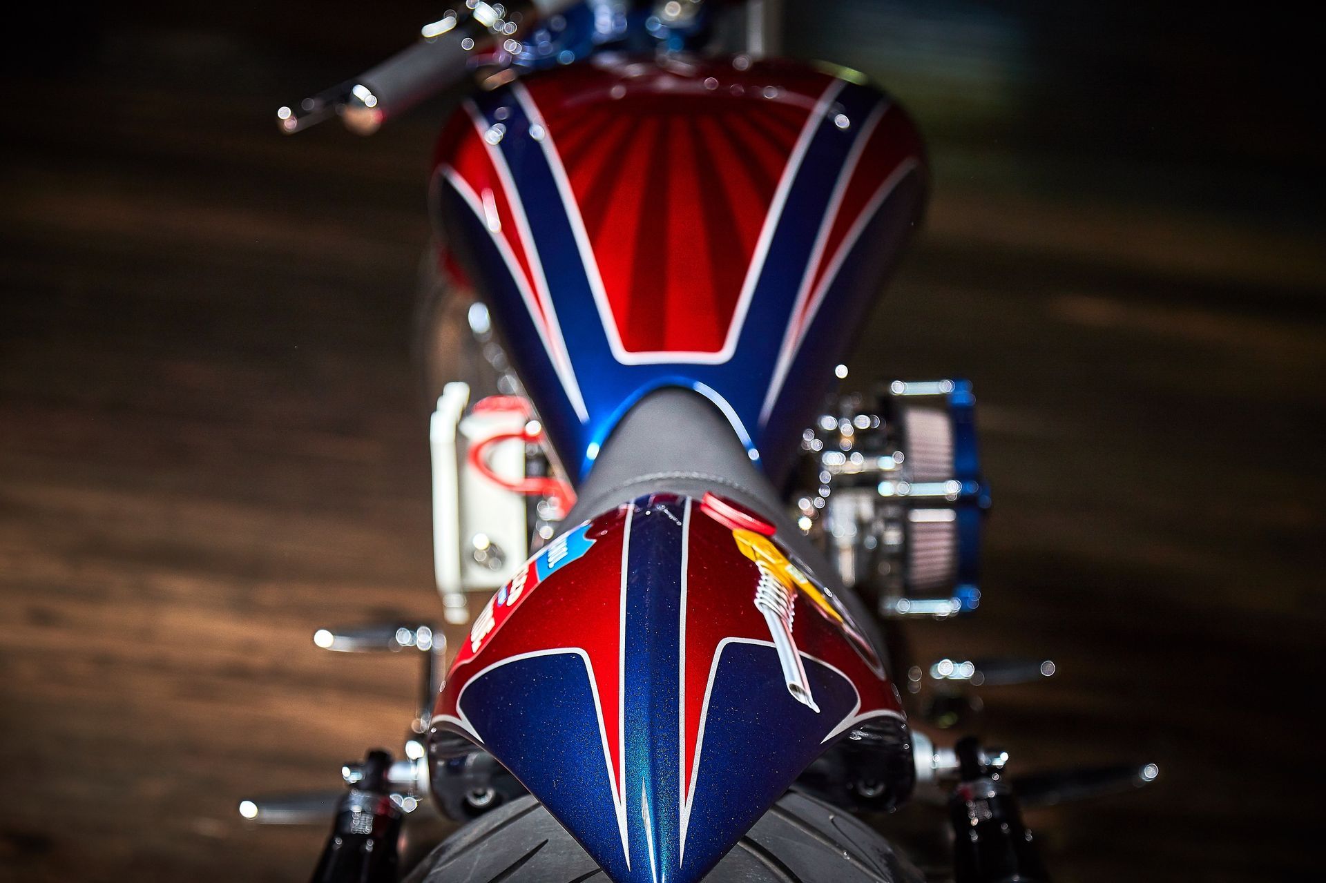 A red , white and blue motorcycle is parked in the dark