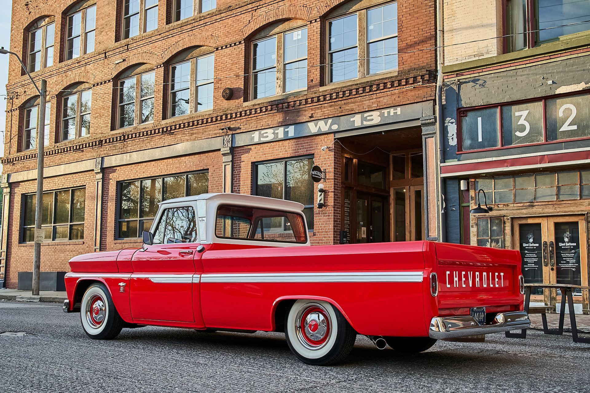 A red truck is parked in front of a brick building.