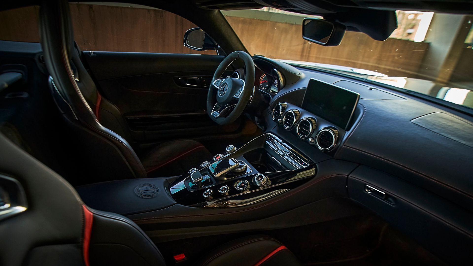 The interior of a black sports car with a steering wheel and dashboard.
