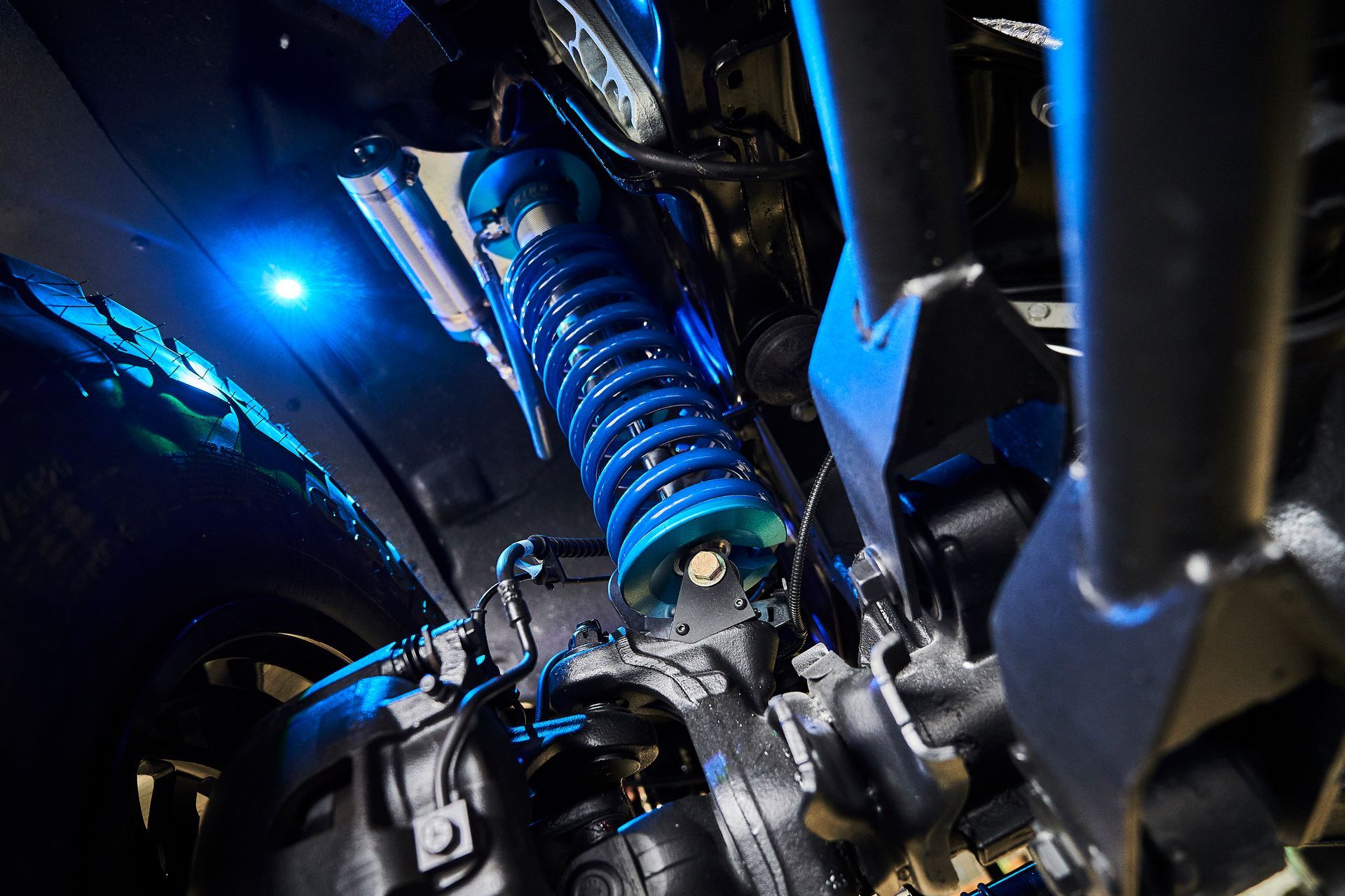 A close up of a shock absorber on a vehicle with blue lights.
