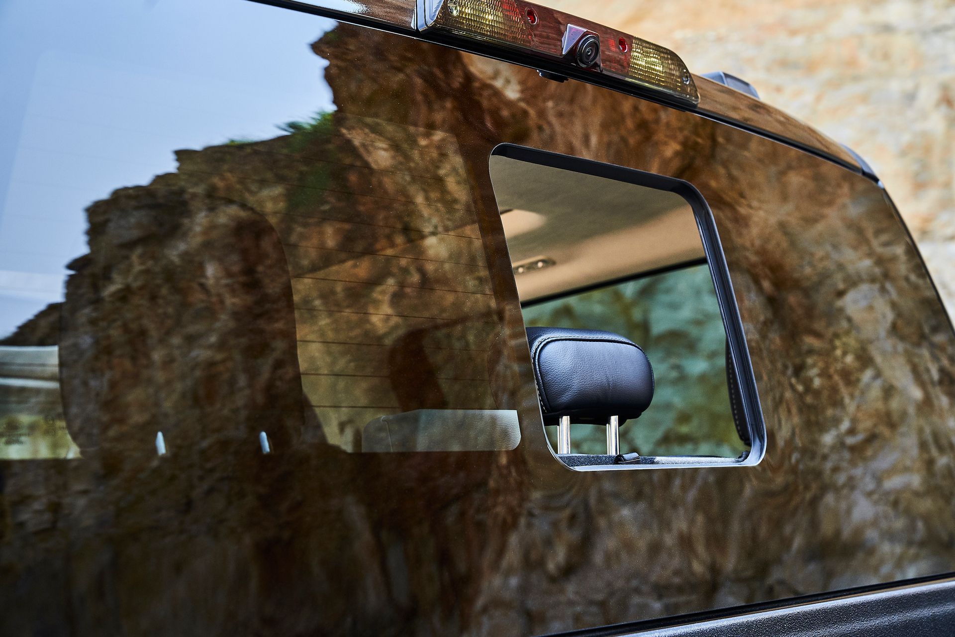 A car with a reflection of a rock in the window.