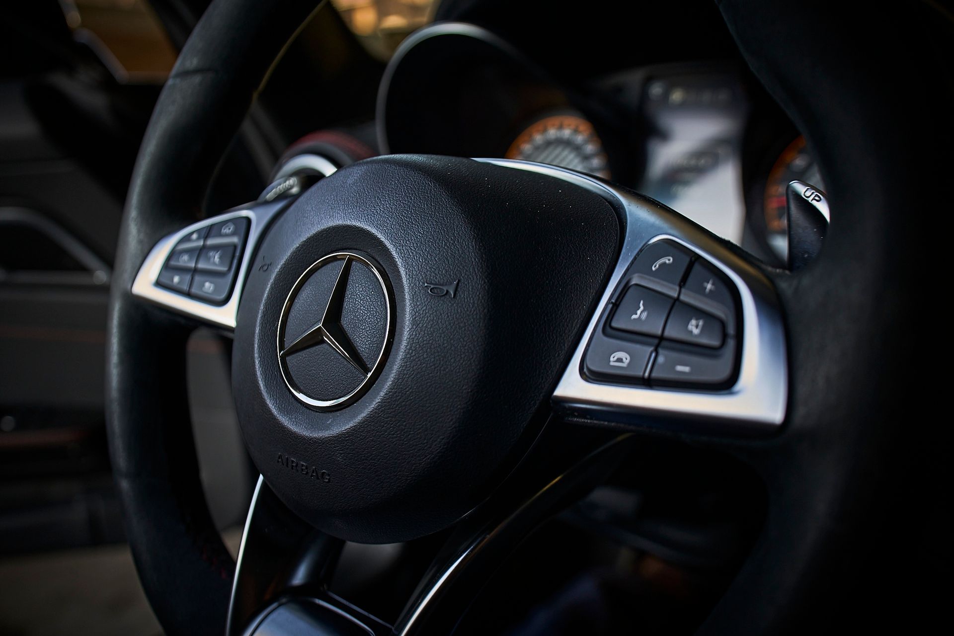 A close up of a mercedes steering wheel with a mercedes logo on it.