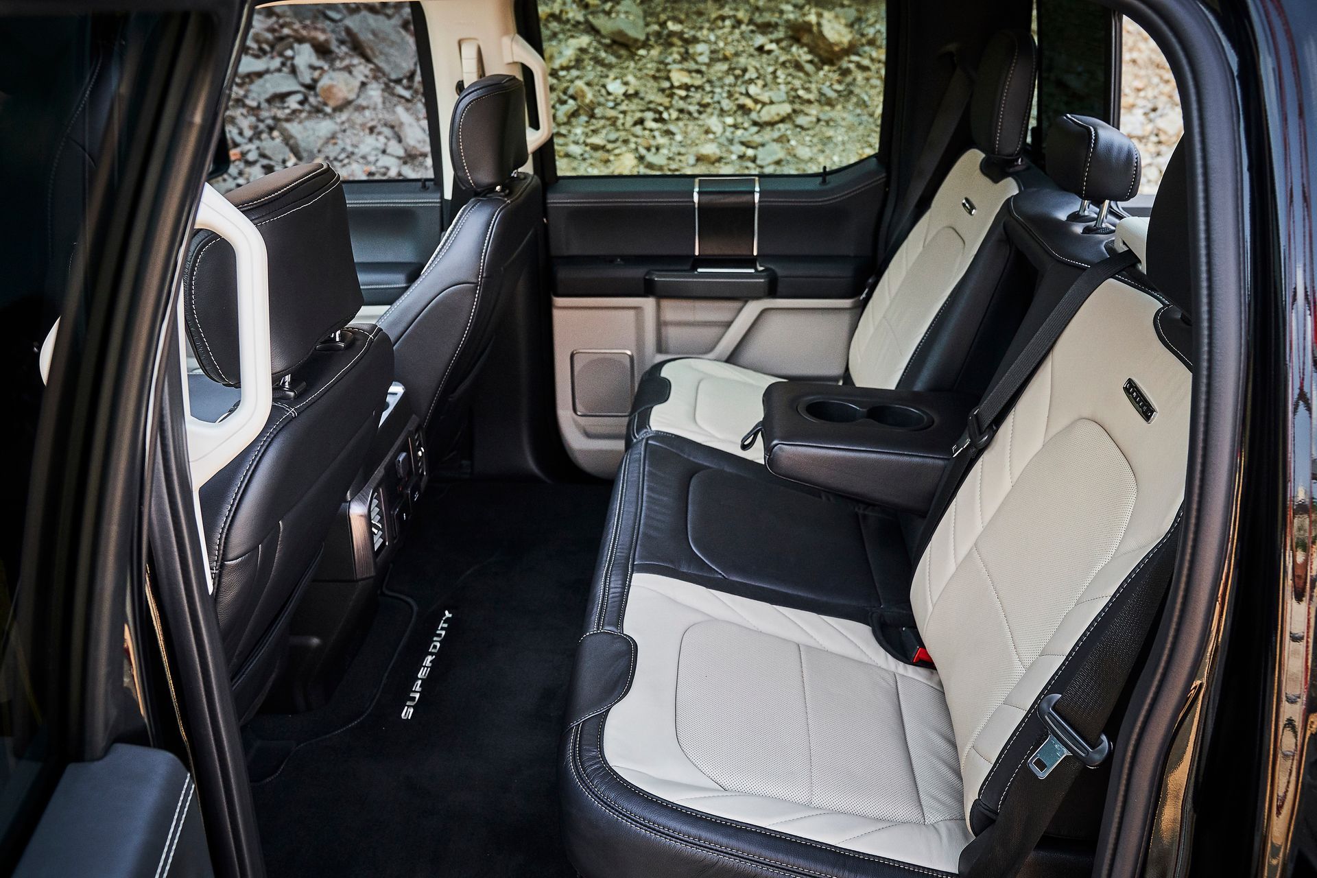 The back seat of a black truck with white seats.