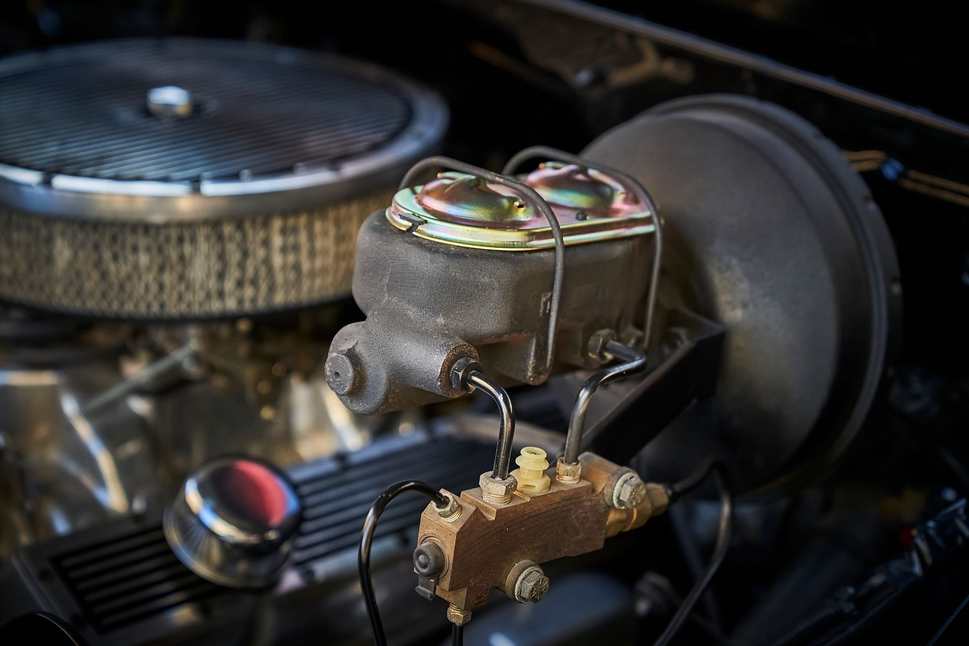 A close up of a car engine with a brake master cylinder.