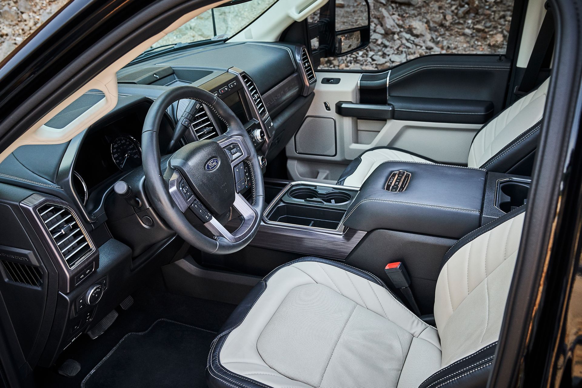 The interior of a black truck with white seats and a steering wheel.