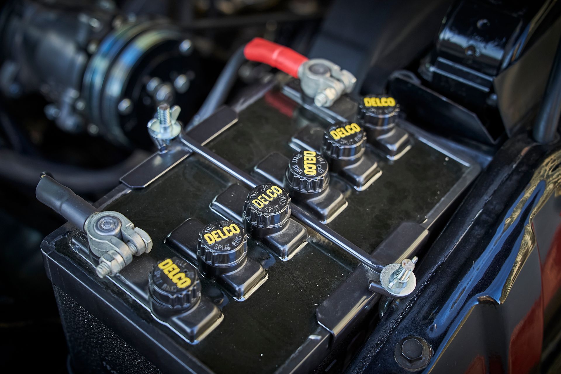A close up of a car battery in the engine compartment.