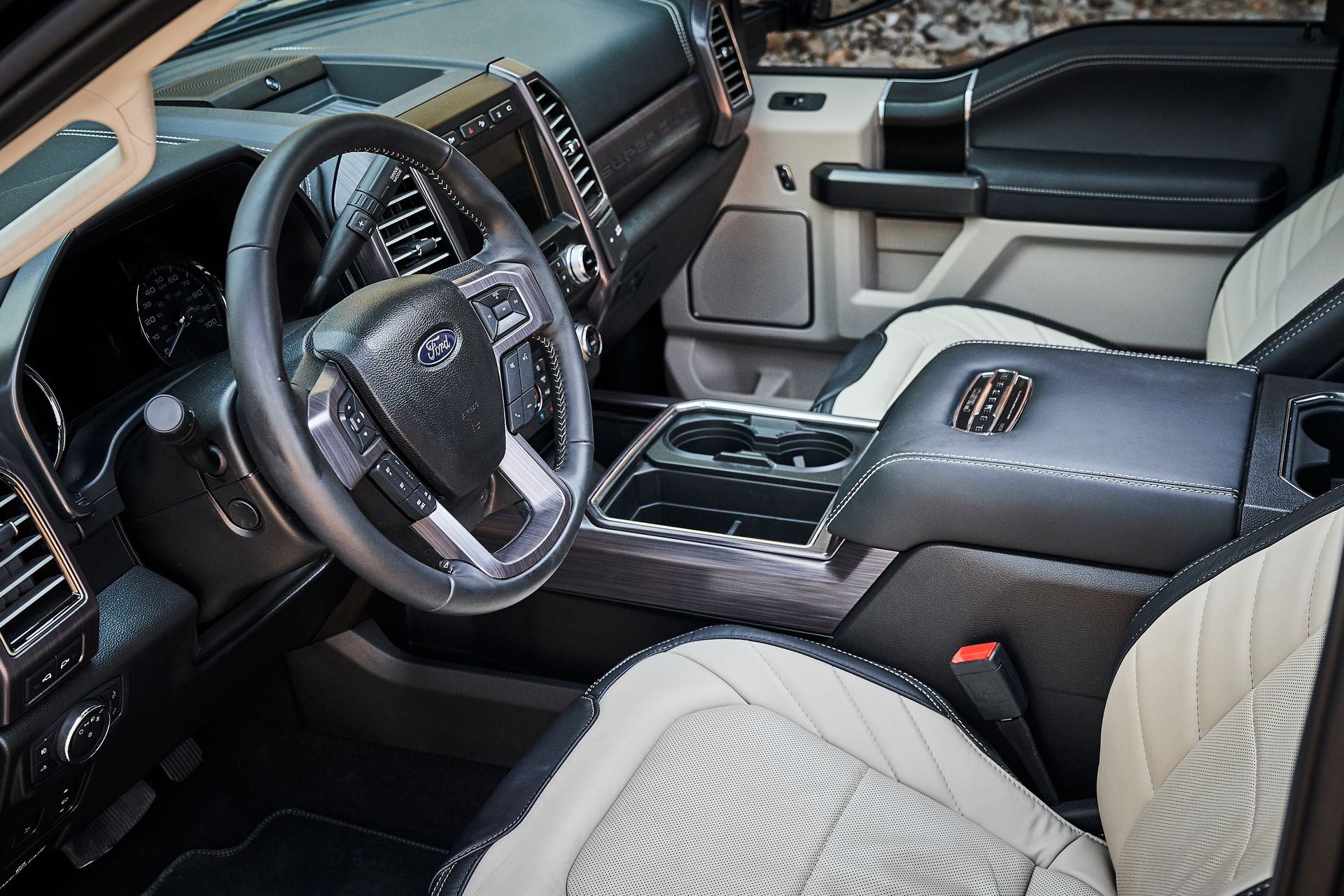 The interior of a ford truck with black and white seats and a steering wheel.