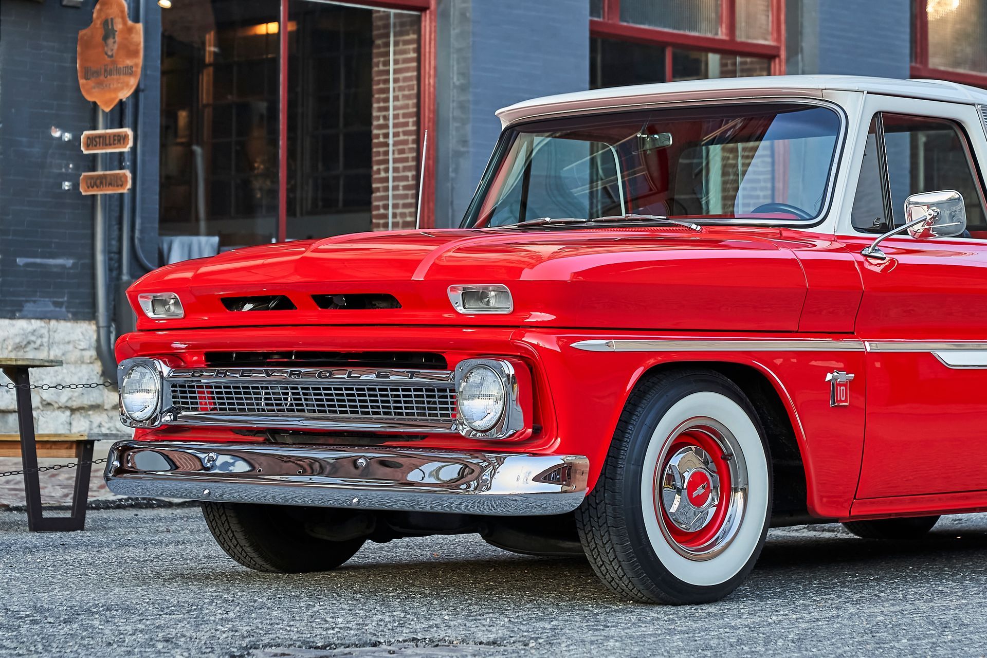 A red truck with white tires is parked in front of a building.