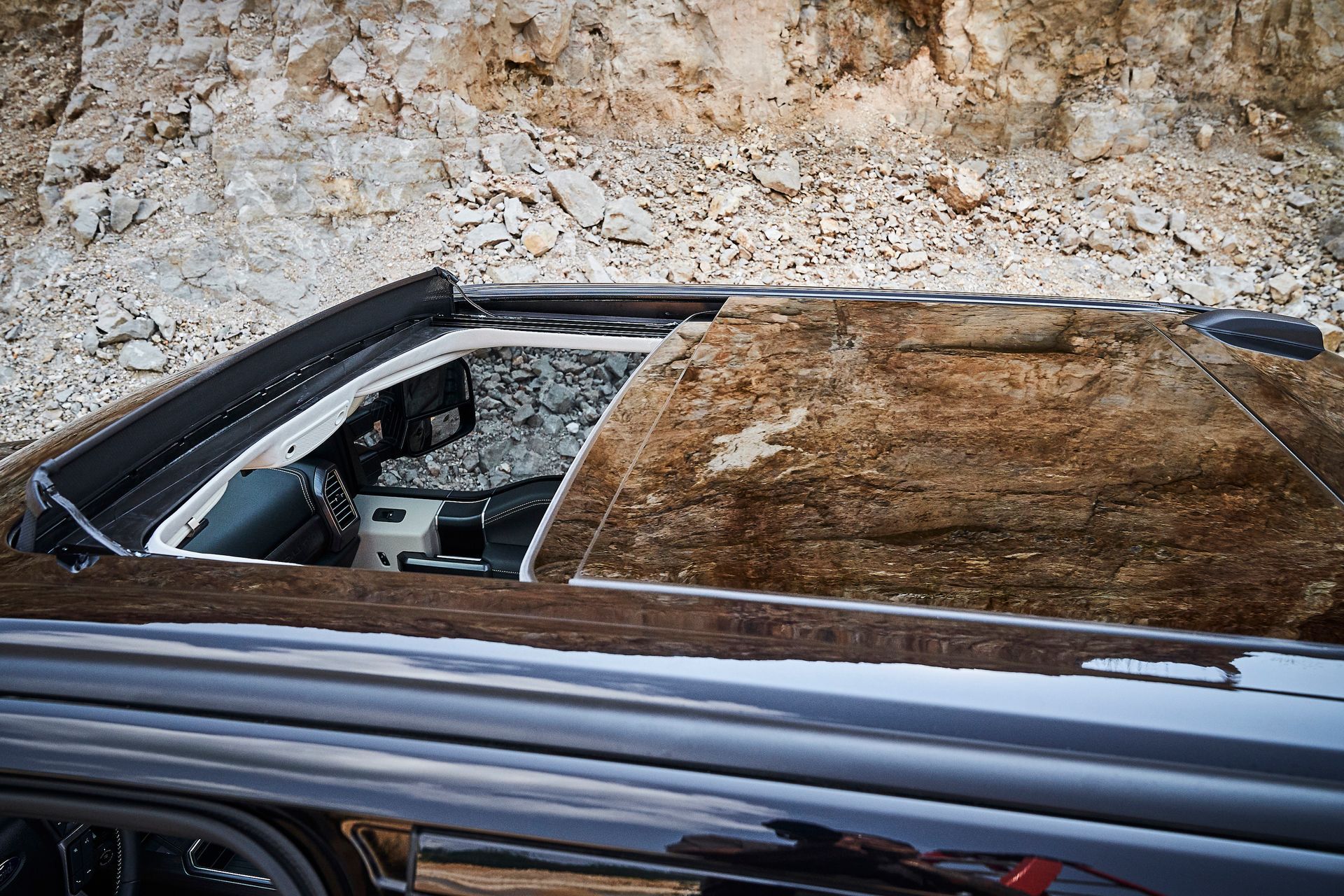 The sunroof of a car is open and covered in dirt.