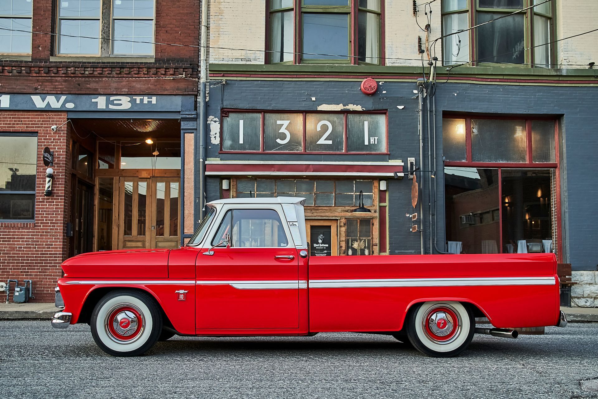 A red truck is parked in front of a building with the number 1312 on it