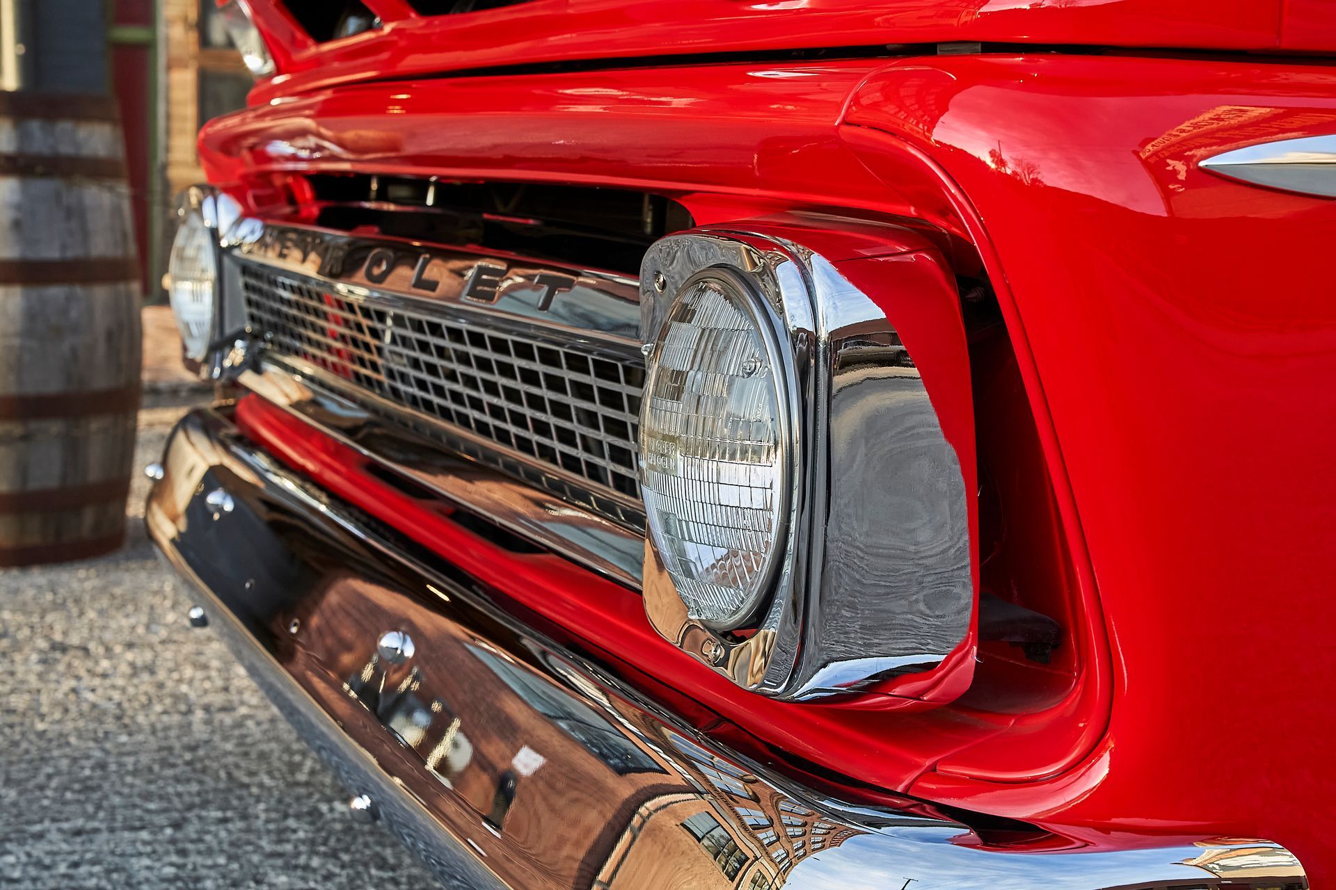A close up of a red truck 's front bumper and headlights.